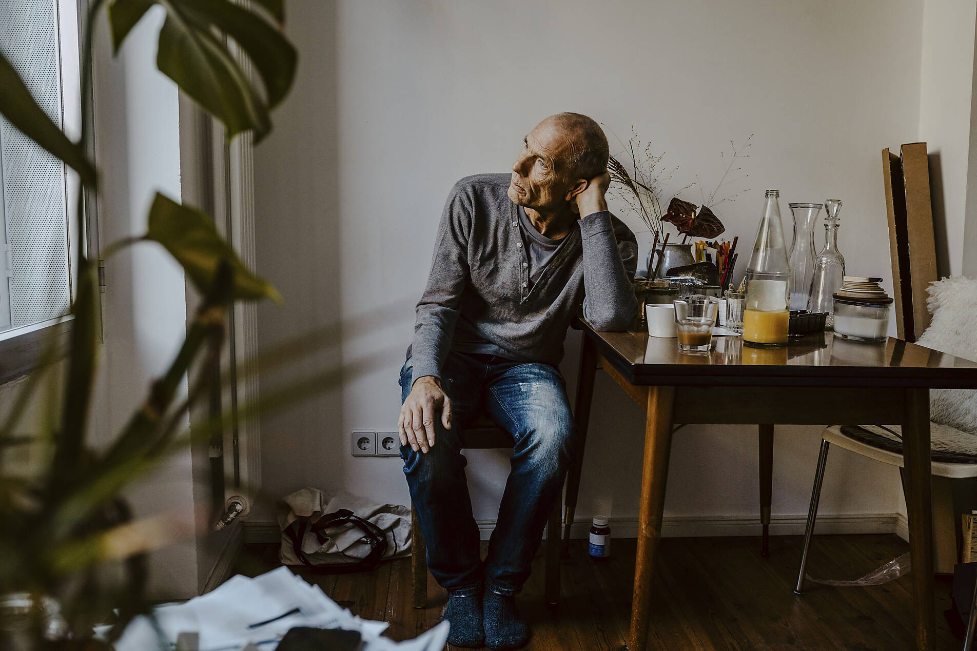 Stockfoto, lizenzfrei, Nachdenklicher älterer Mann sitzt auf einem Stuhl im Wohnzimmer
