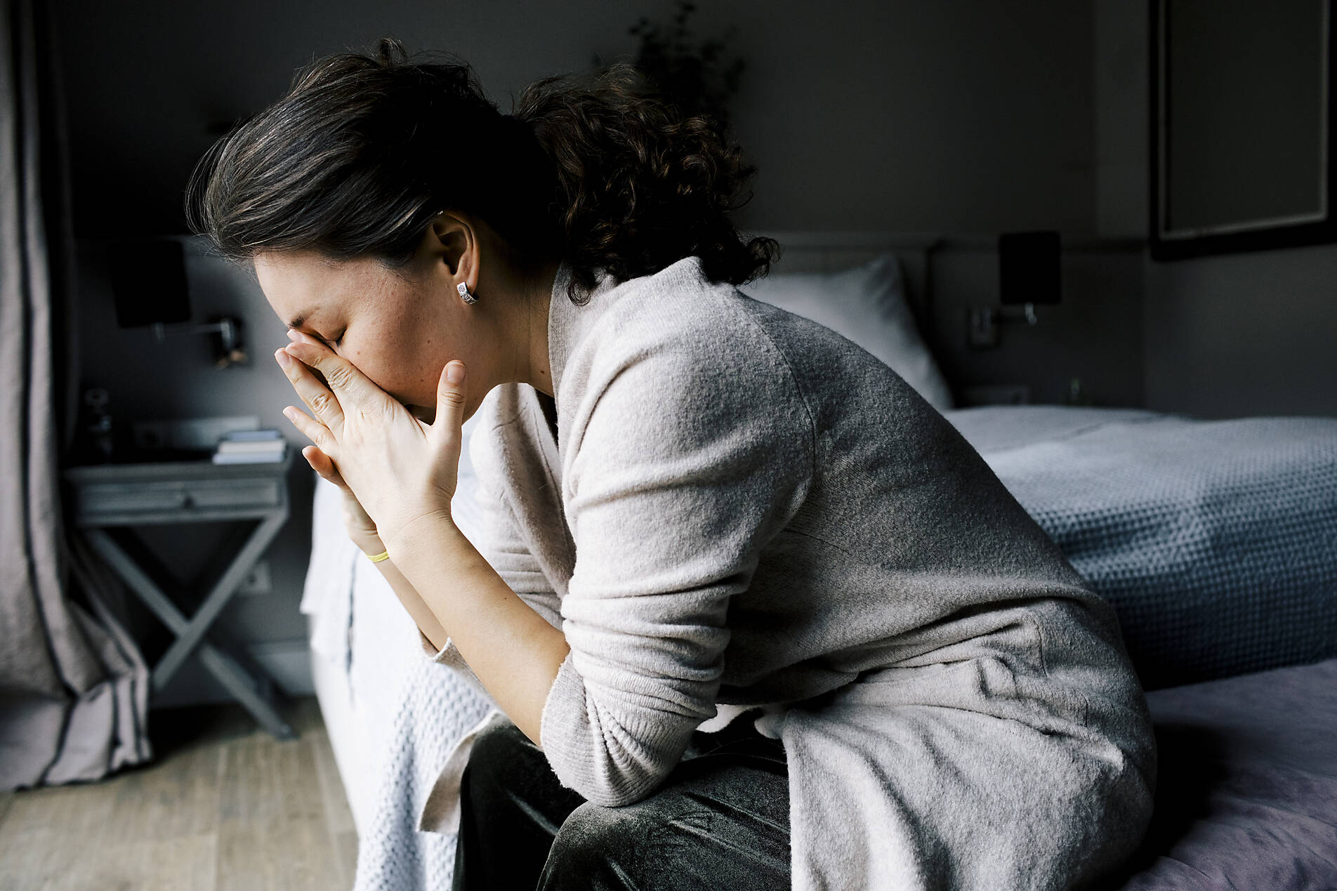 stockfoto, lizenzfrei, Seitenansicht einer einsamen, ängstlichen Frau, die zu Hause am Bett sitzt