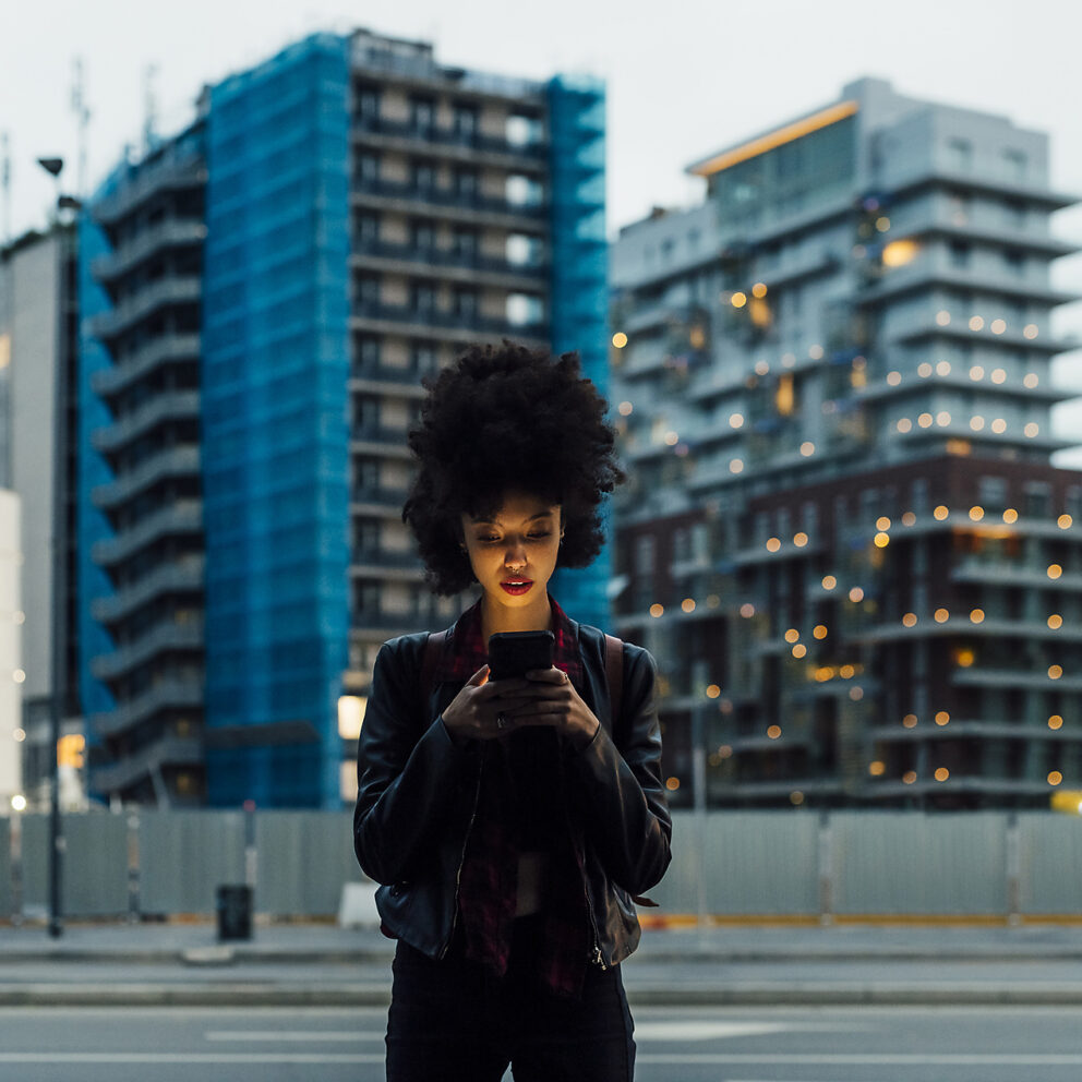Lizenzfreie Stockfotos, vertikale Bilder, Smartphone, mobile-first, Frau, die ein Mobiltelefon benutzt, während sie in der Stadt steht