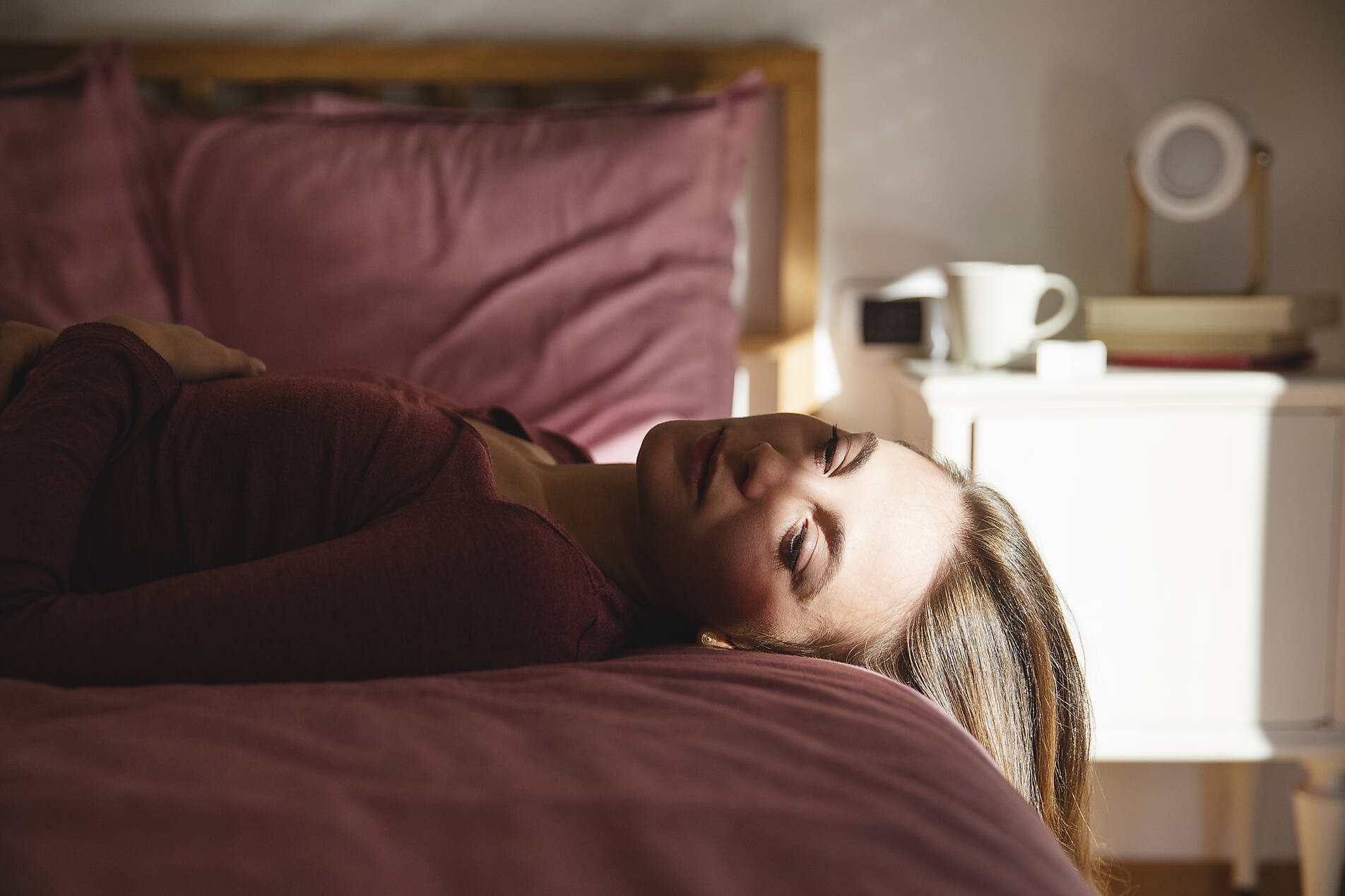 Stockfoto, lizenzfrei, Traurige junge Frau liegt zu Hause auf dem Bett