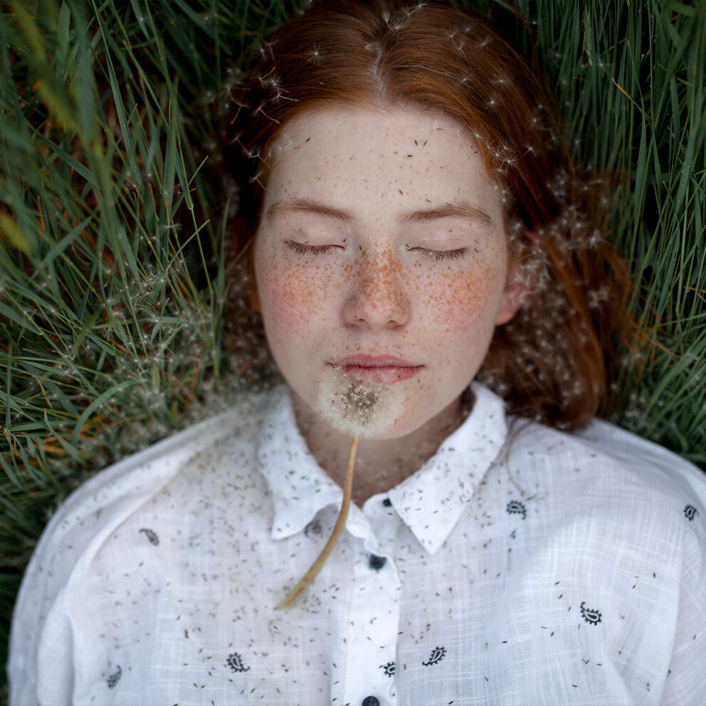 Stockfoto, lizenzfrei, Teenager-Mädchen liegend mit Löwenzahn-Samenkopf