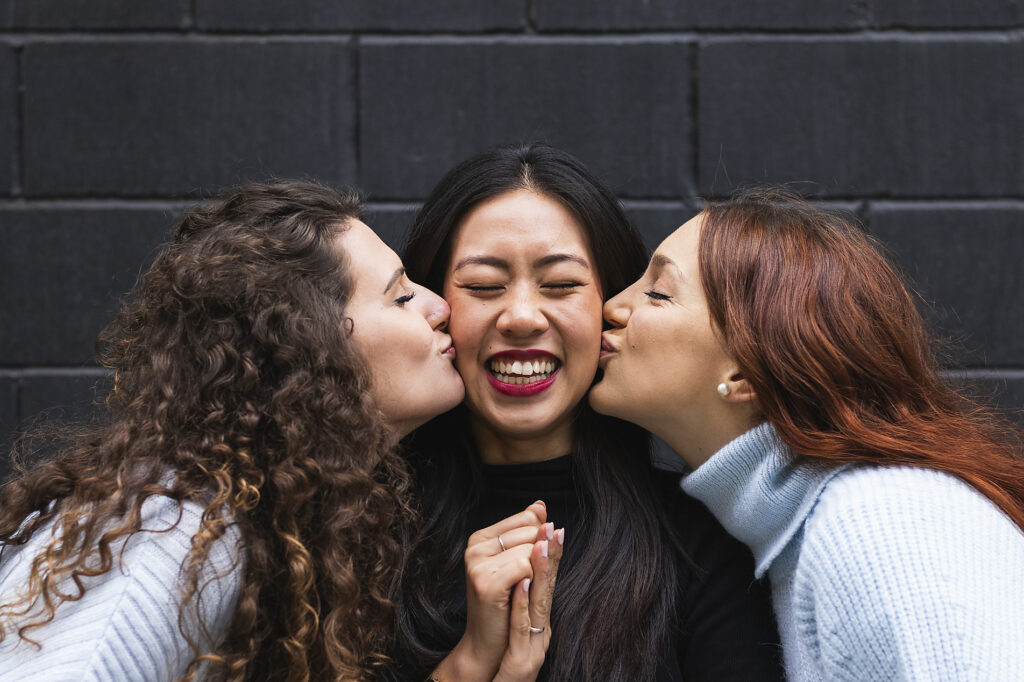 stock image, royalty-free, Young female friends kissing happy woman