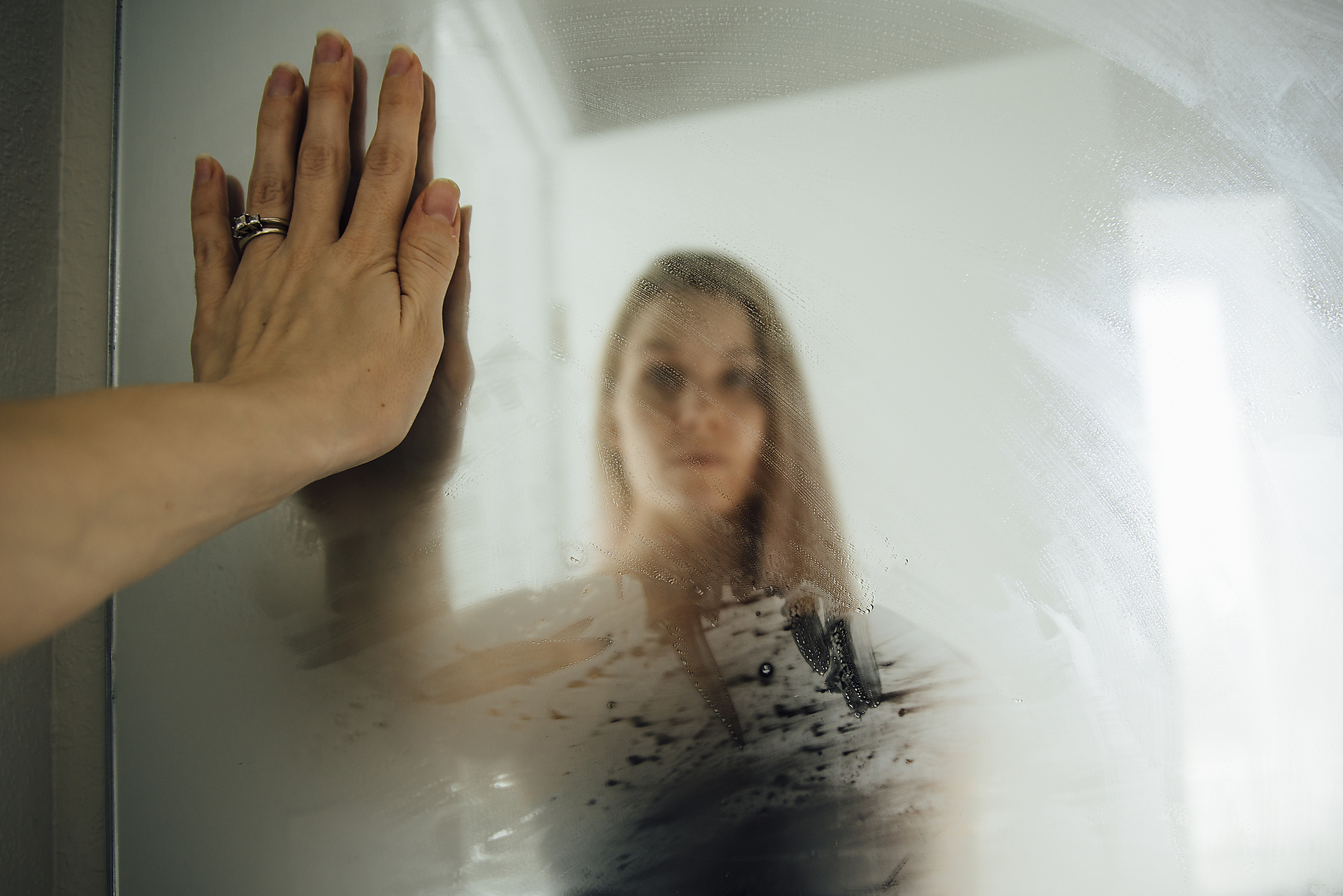 Stockfoto, lizenzfrei, Frau mit Ehering schaut zuhause in nassen Badezimmerspiegel