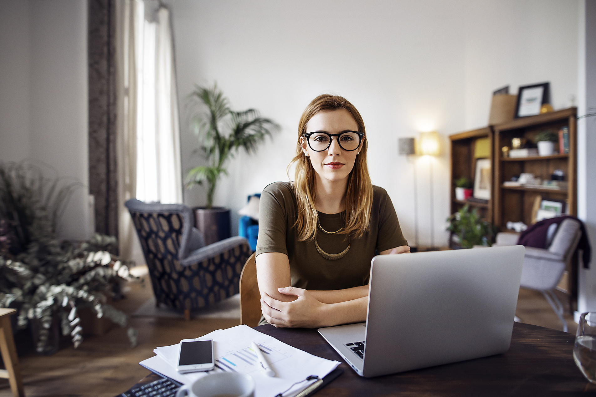 Stockfoto, lizenzfrei, New Work, Porträt einer selbstbewussten Geschäftsfrau, die mit einem Laptop an einem Tisch im Büro sitzt