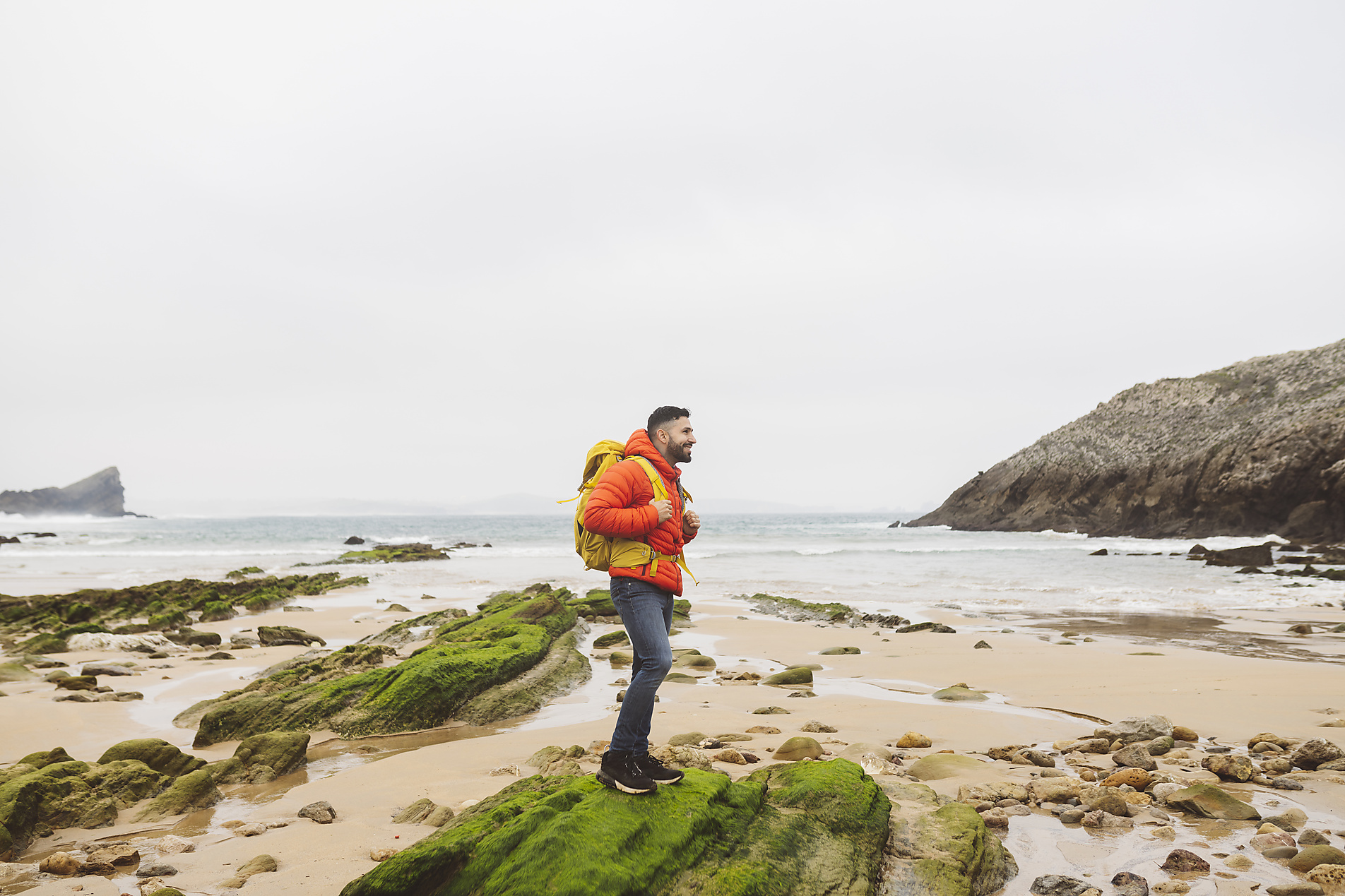 stock image, royalty-free, Man wearing backpack standing on rock at beach
