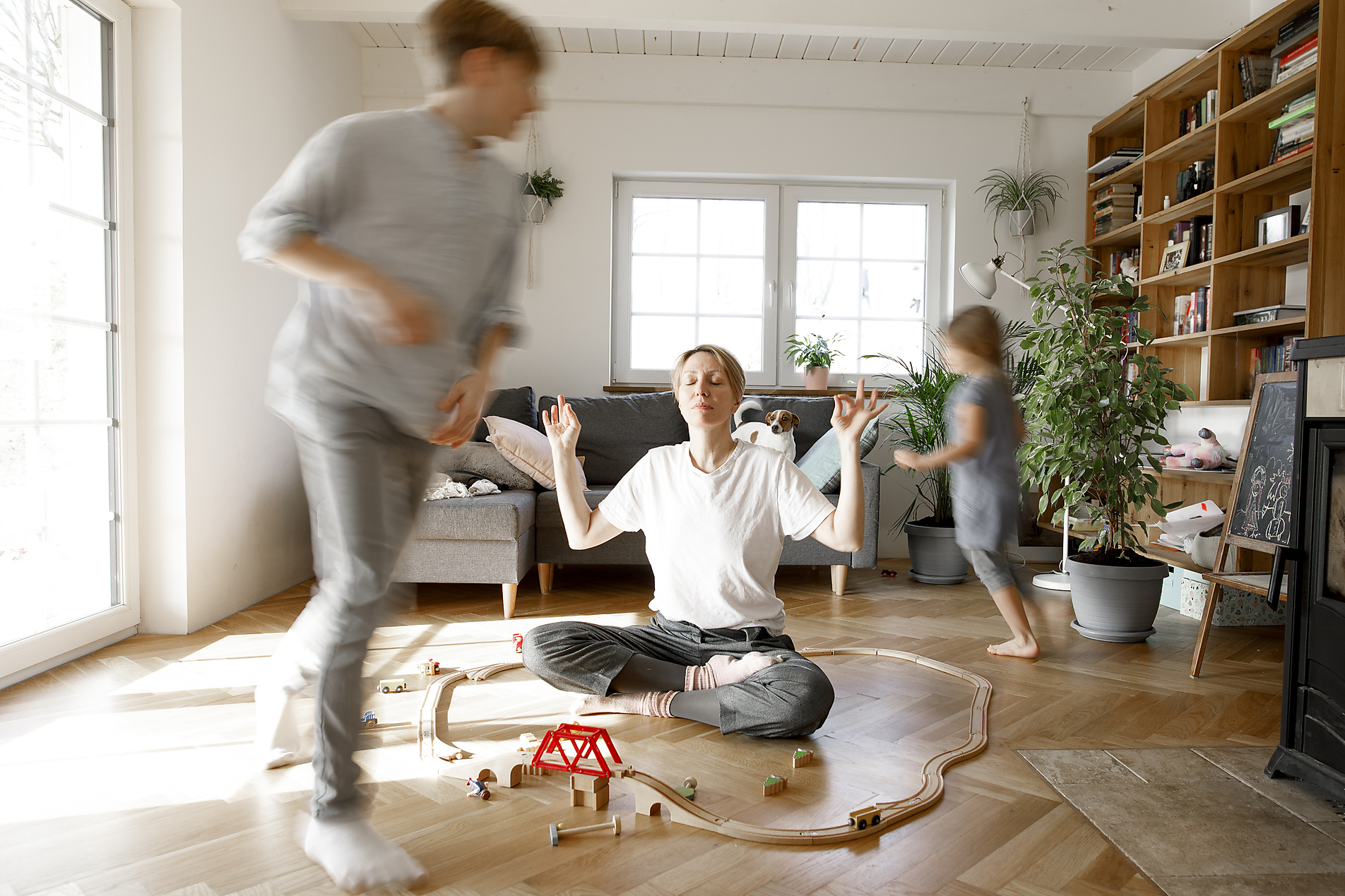 Mother meditating in the middle of toys, whilchirdren are running around her, stock photo, royalty-free,