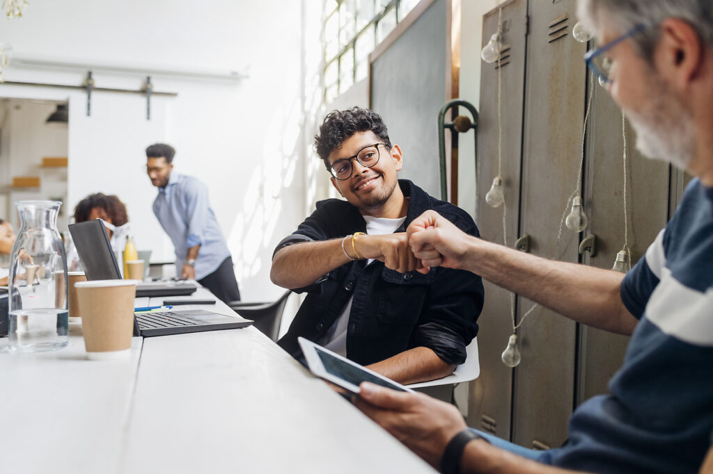 Stock image, royalty-free, Smiling businessman giving fist bump to colleague at workplace