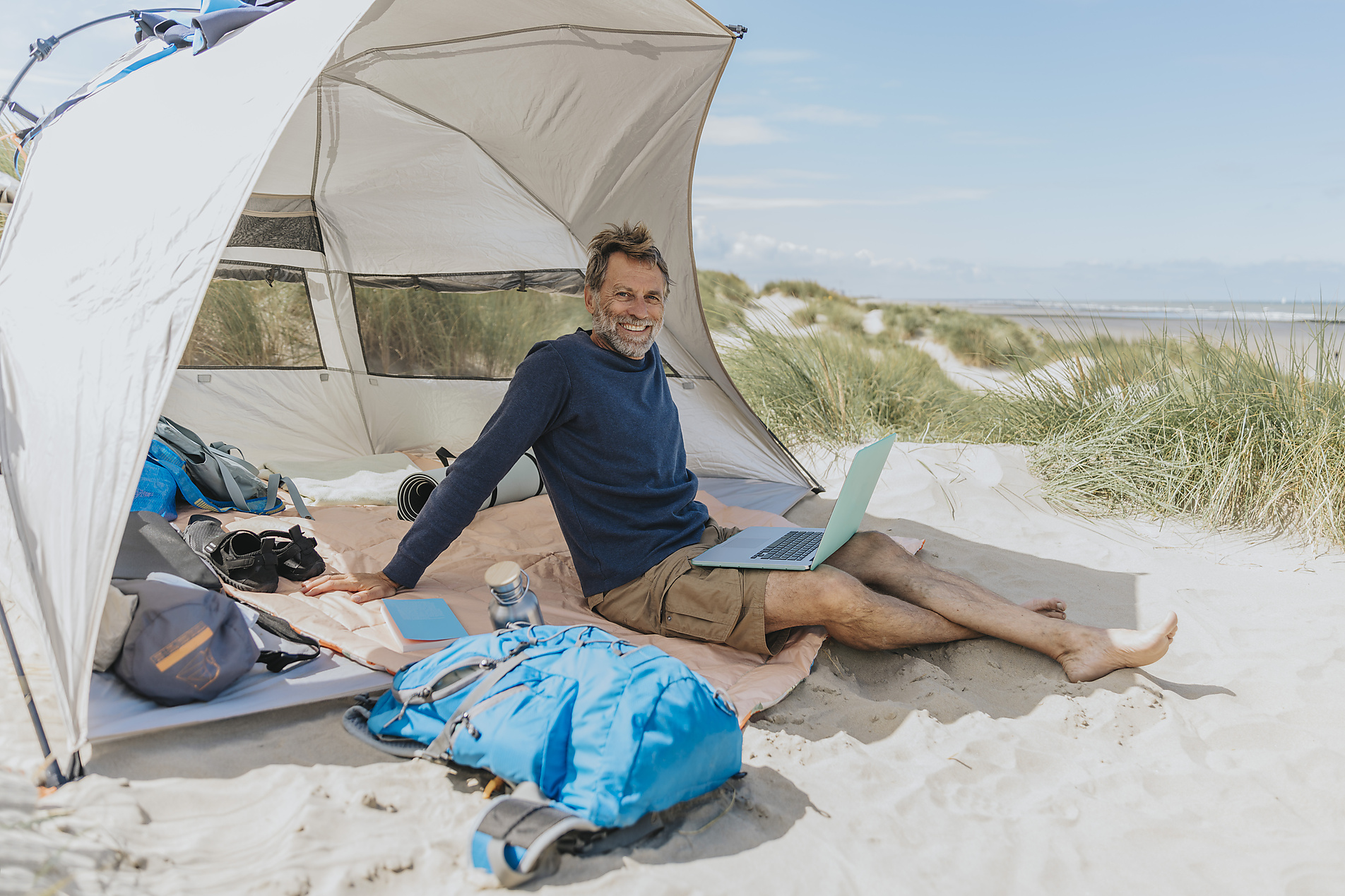 stock image, royalty-free, Happy freelancer with laptop sitting in tent at beach on sunny day