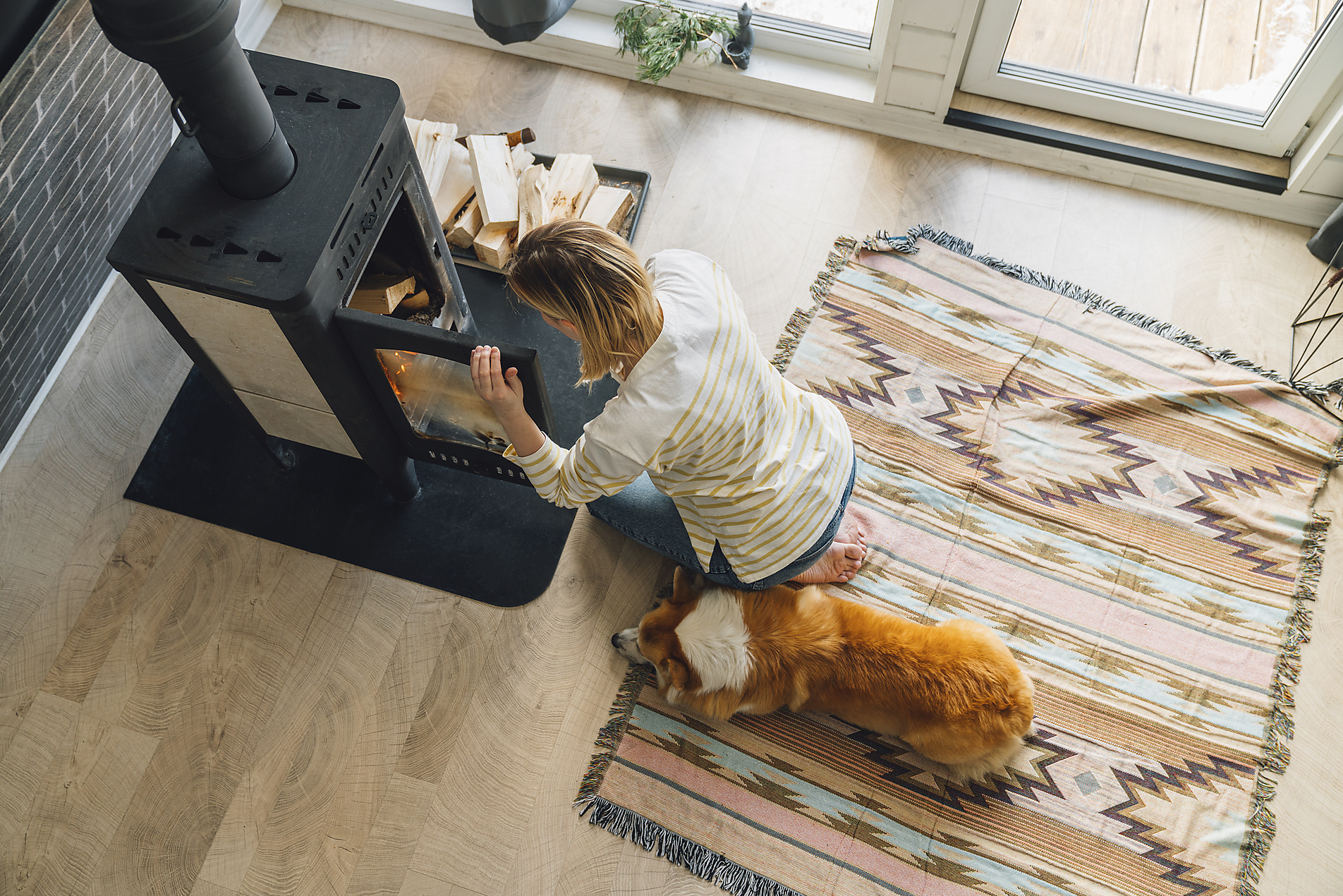 Stock image, royalty-free, Woman sitting near fireplace in living room at home, alternative energy, energy crisis