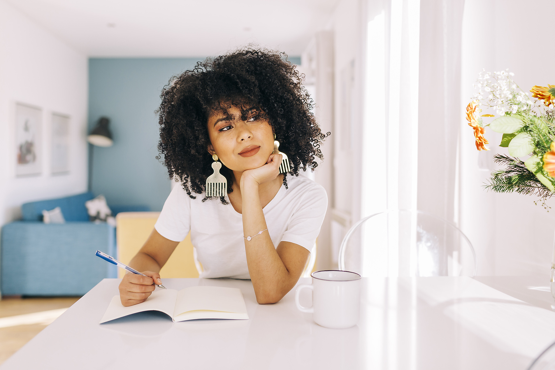 stock image, royalty-free, Portrait of young woman with curly hair sitting at a table with a notebook at home, Alexandra C Ribeiro