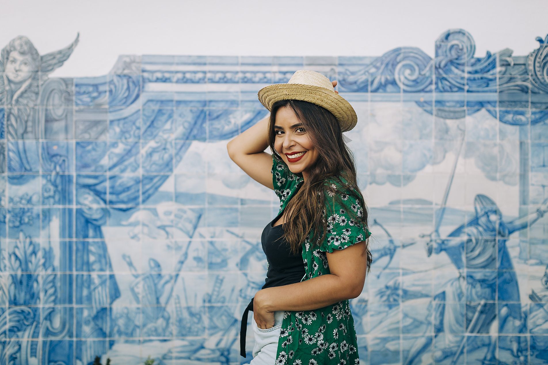 Stock image, royalty-free, Smiling beautiful woman wearing hat standing by Azulejo wall