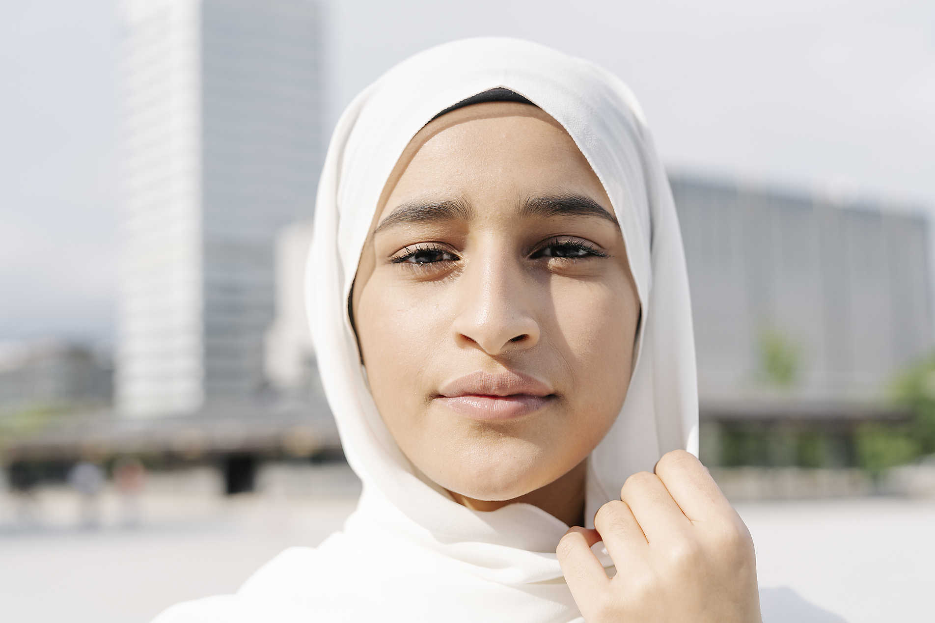 Portrait of a young woman wearing a hijab in a city surrounding, sunny day, stock image, royalty-free