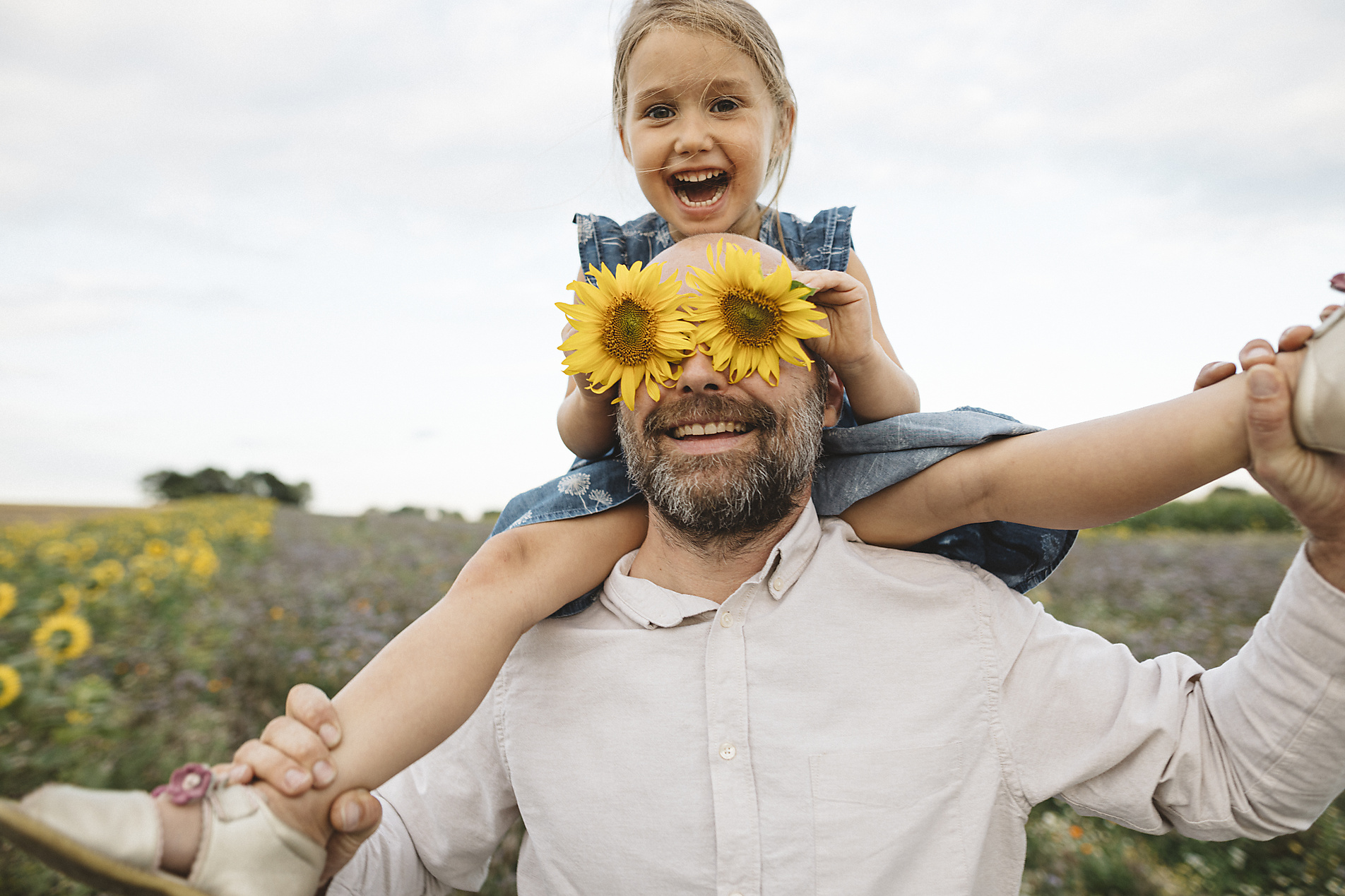 Stock image, royalty-free photography, Katharina Mikhrin, Sunflowers covering eyes of playful man with daughter in a field, Inspiration