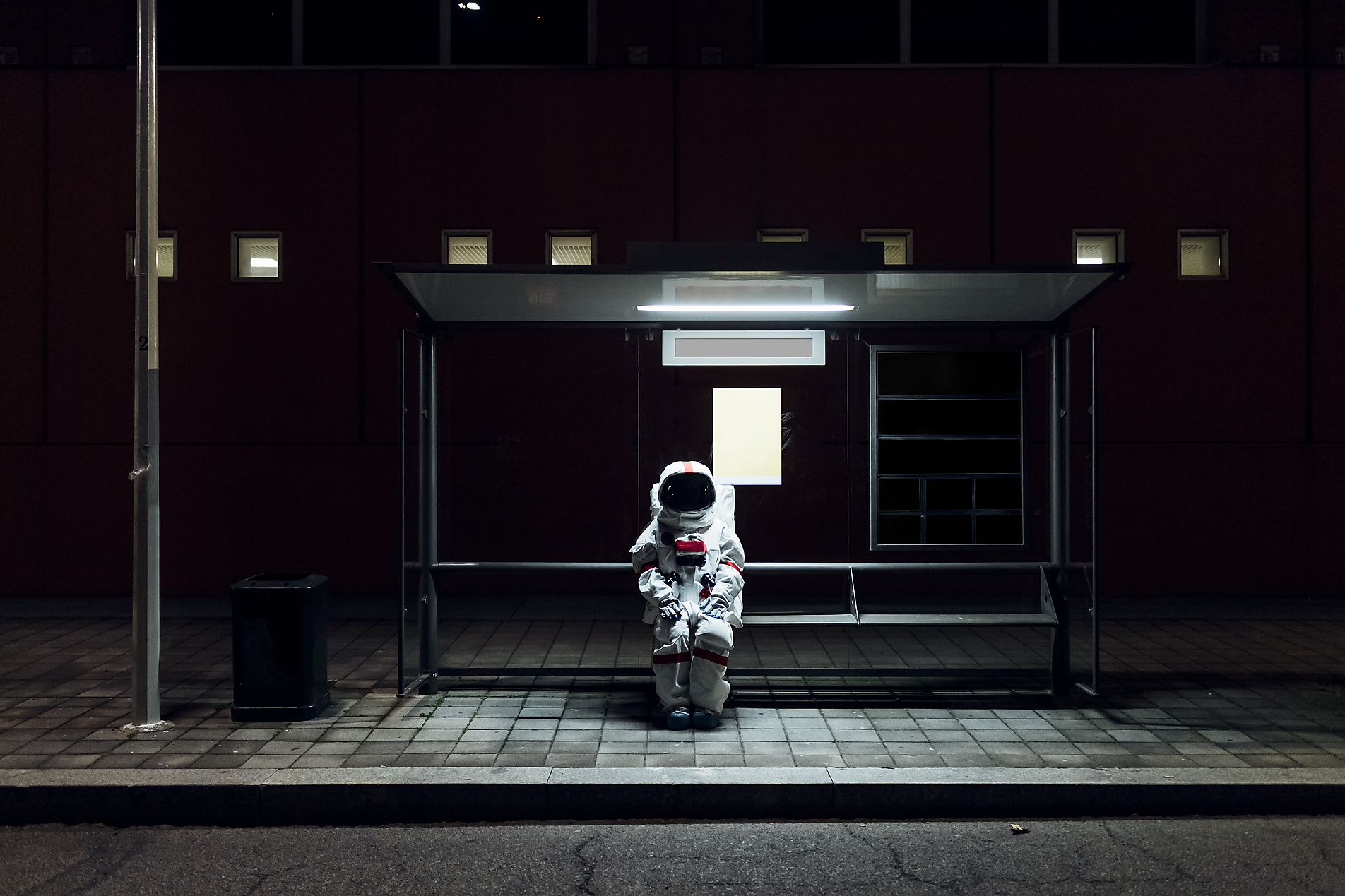 stock image, royalty-free, pau novell, Female astronaut sitting at bus stop during night