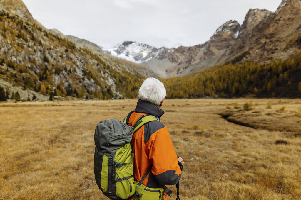 stock image, royalty-free, Senior backpacker looking at mountains at Rhaetian Alps, Italy, Autumn