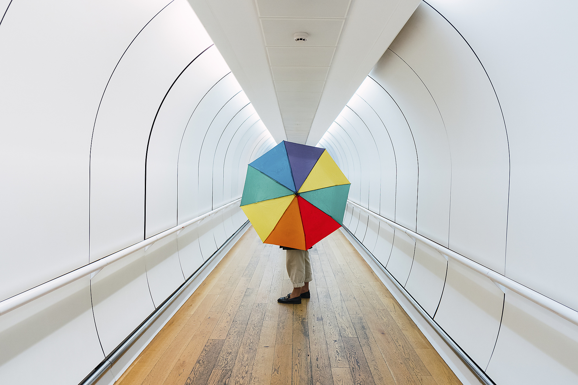 stock image, royalty-free, Pau Novell, Young woman with multi colored umbrella standing on walkway