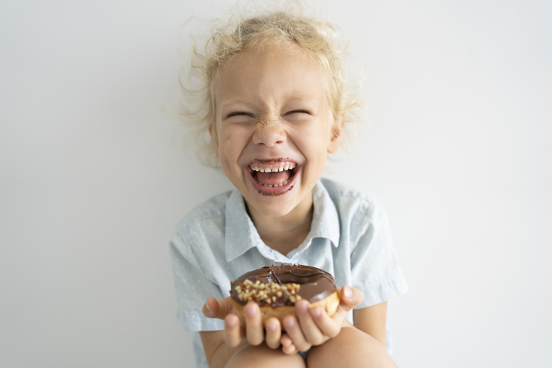 stock image, royalty-free, Cheerful girl holding doughnut laughing at home, Svetlana Karner