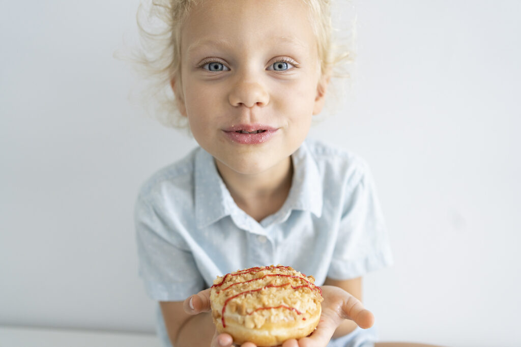 Stockfoto, lizenzfrei, Mädchen mit Krapfen vor einer Wand sitzend, Svetlana Karner