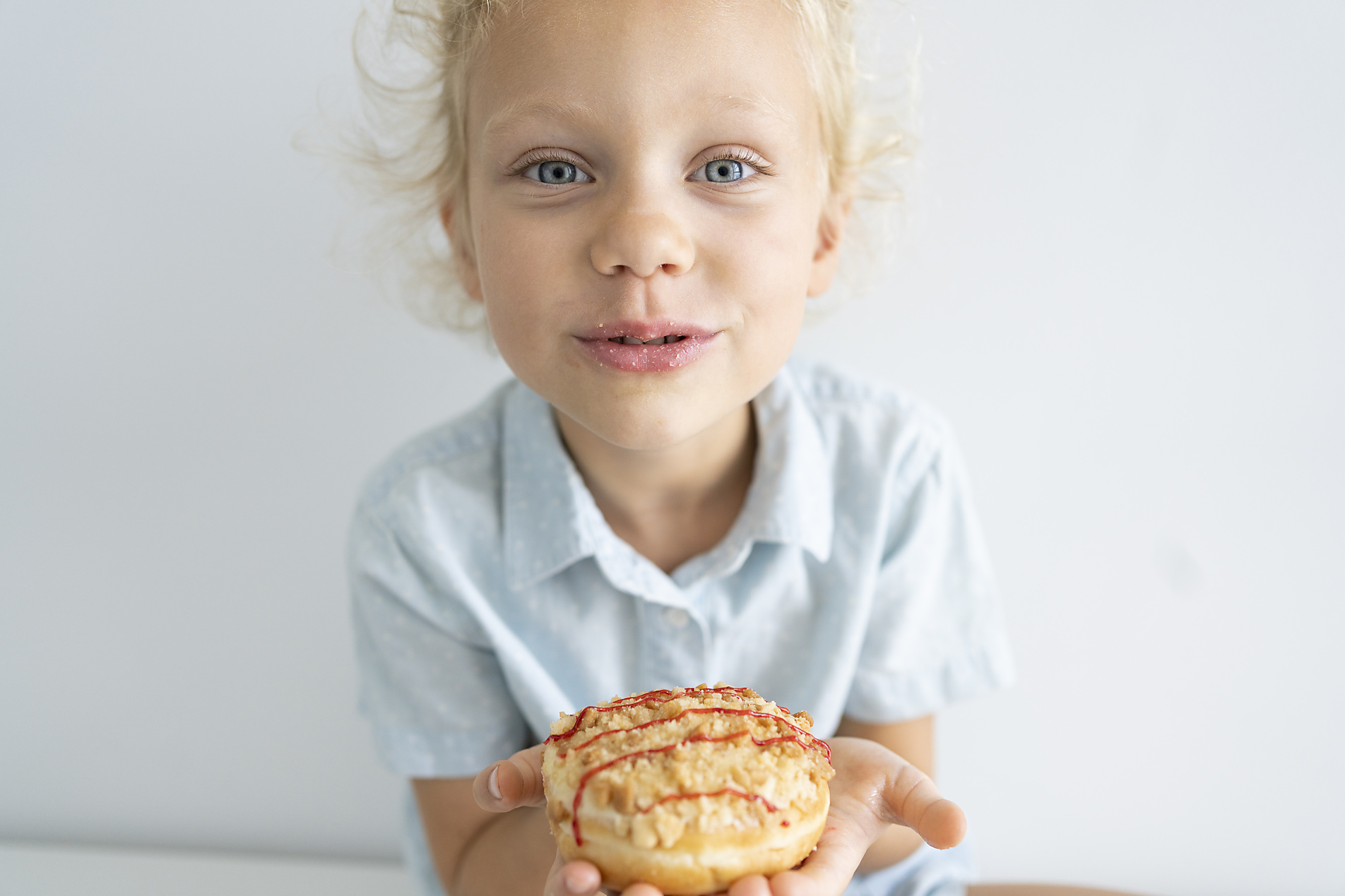 Stock image, royalty-free, Girl holding doughnut sitting in front of wall at home, Svetlana Karner