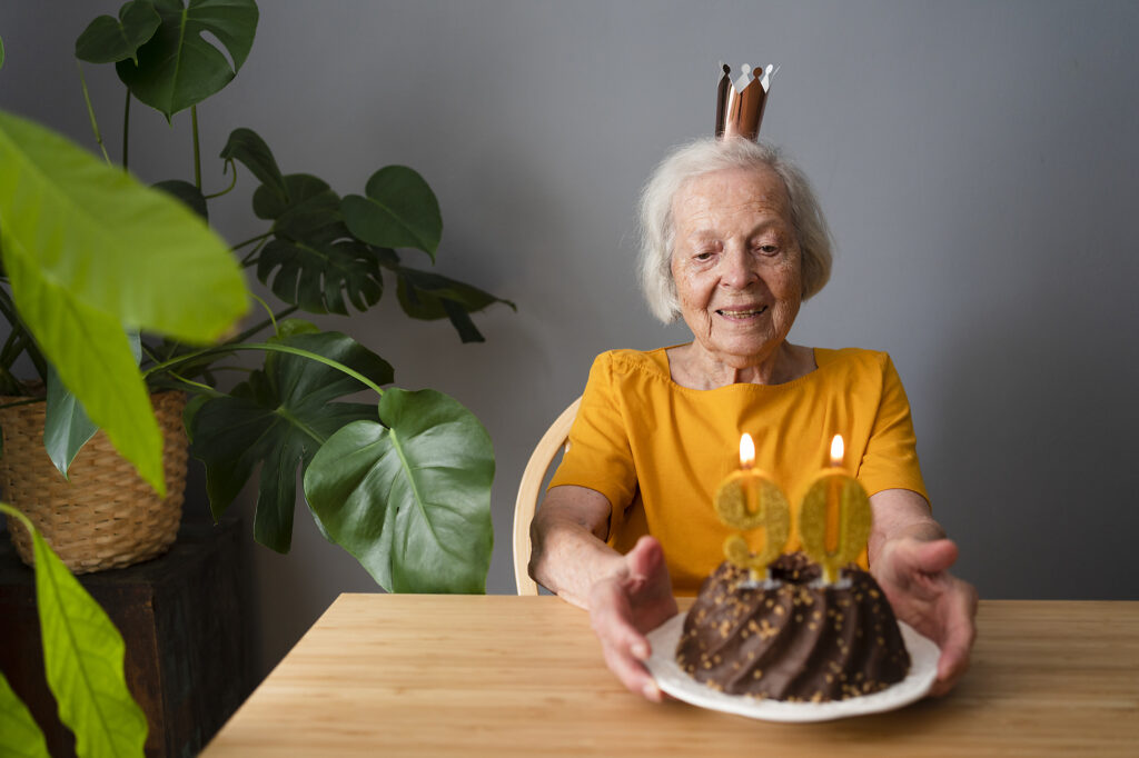 stockfoto, lizenzfrei, Lächelnde ältere Frau feiert Geburtstag mit Kuchen zu Hause, Svetlana Karner