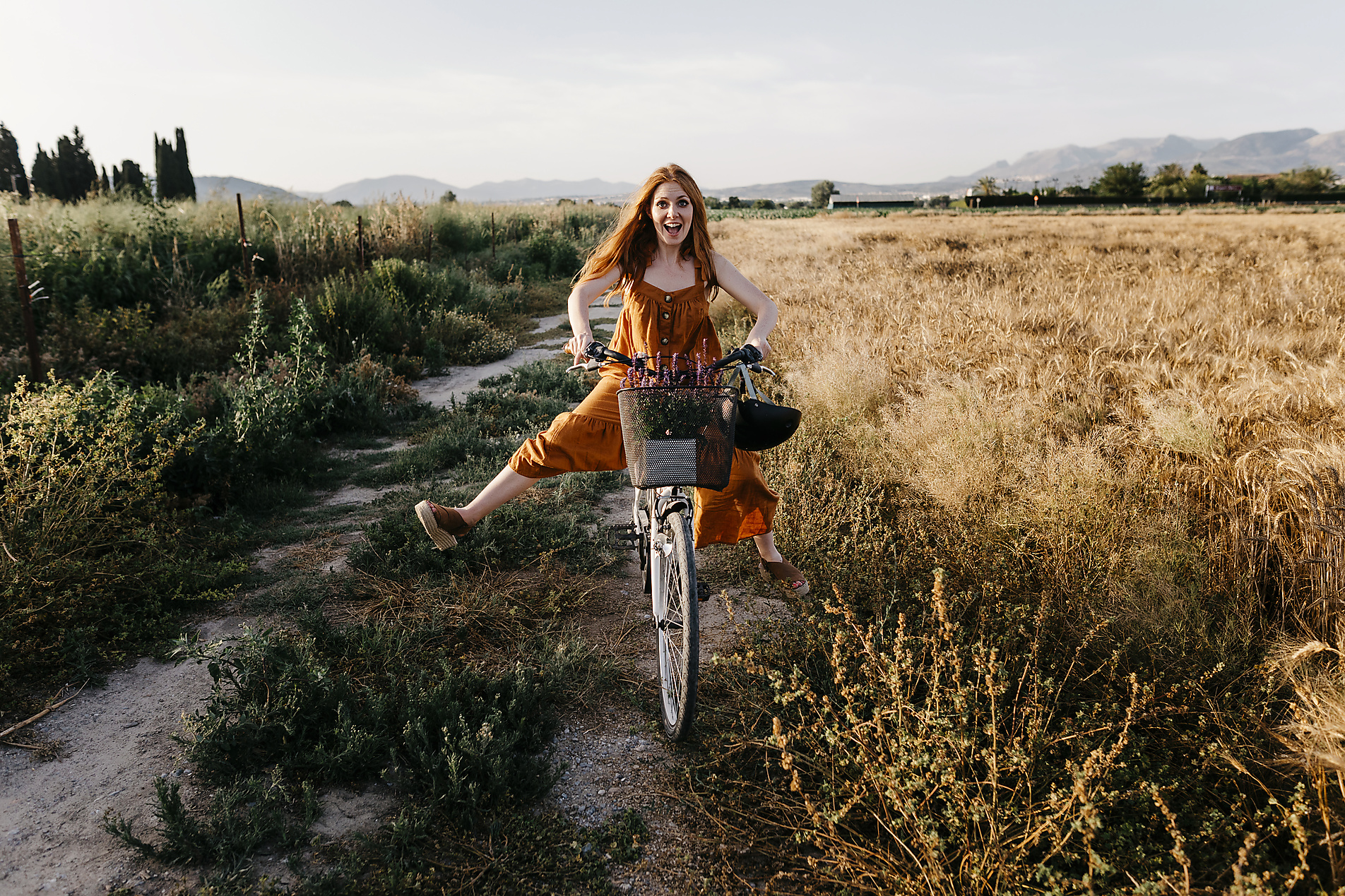 Stockfoto, lizenzfrei, Unbekümmerte Frau fährt Fahrrad in landwirtschaftlichem Feld, Tania Cervián