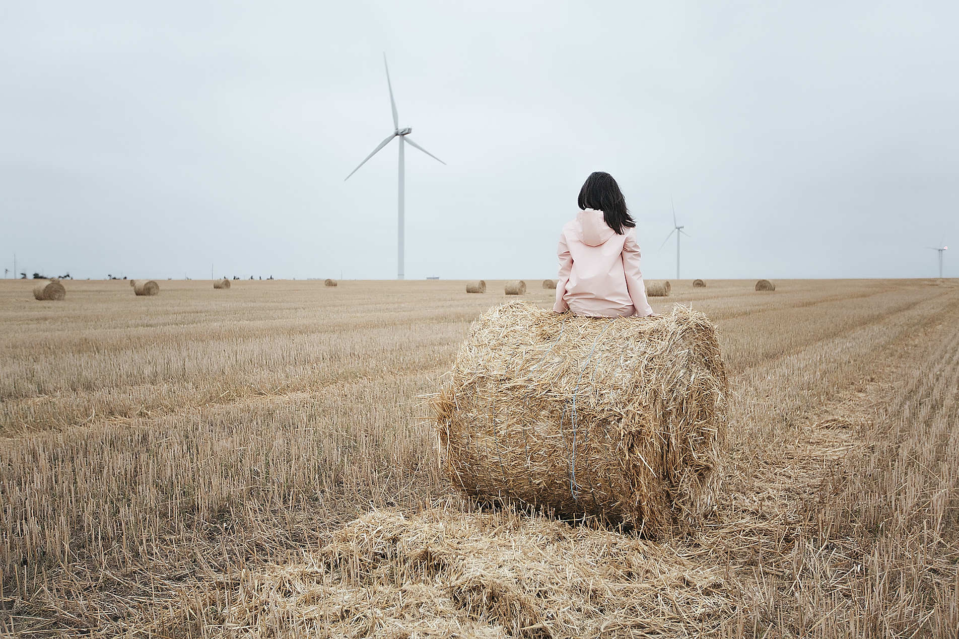 stock image, royalty-free, Woman in raincoat on hay bale, Odessa, Ukraine, Westend61, Image Source RF / Rehulian Yevhen