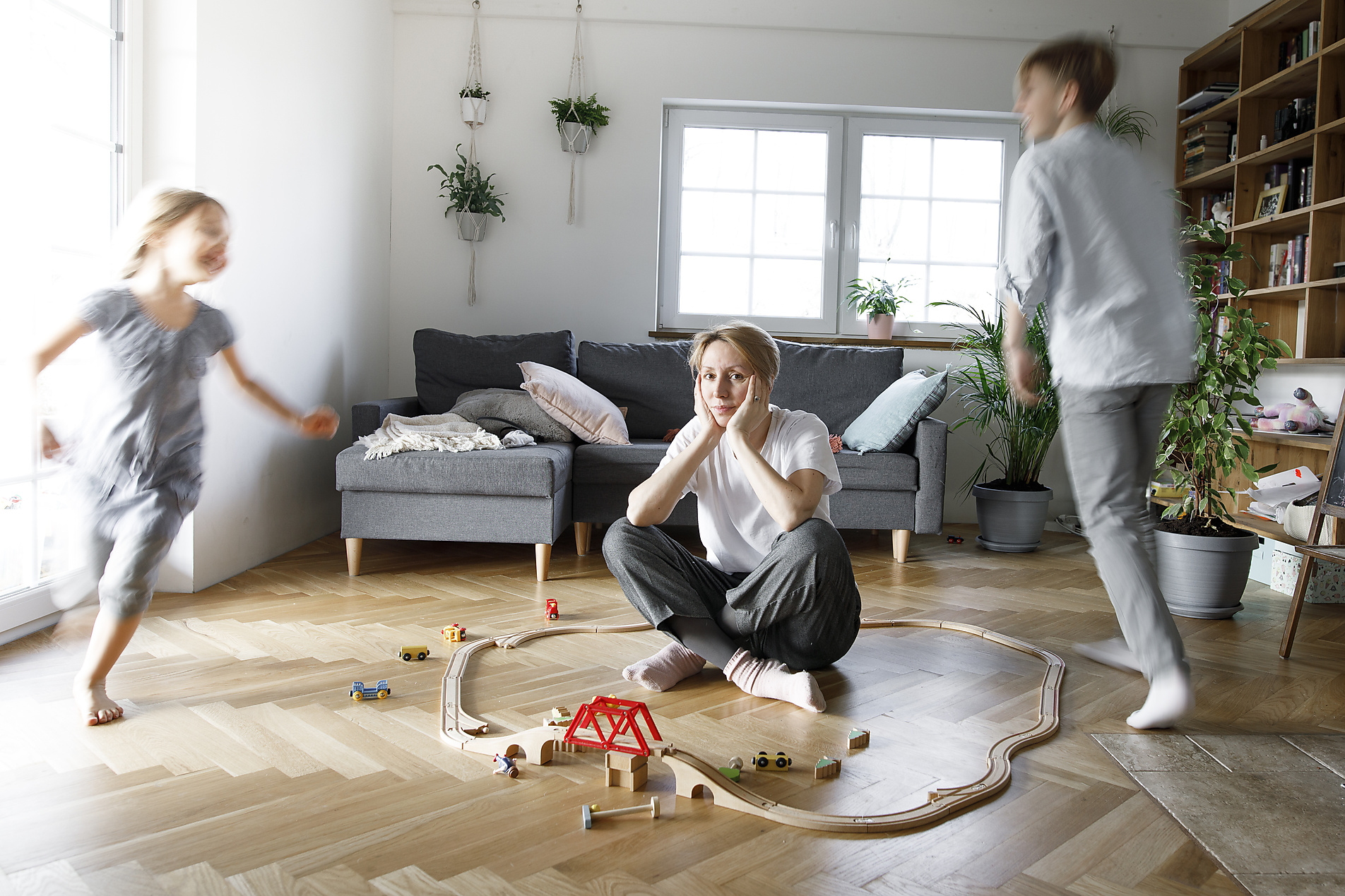 stock image, royalty-free, Stressed out mother sitting in the middle of toys, while children are running around her, Westend61, Katharina Mikhrin