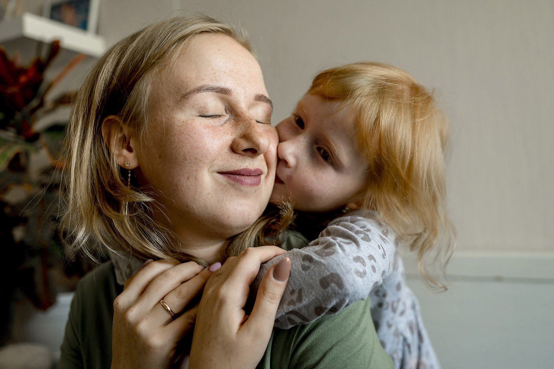 Stock photo, royalty free, family, security, changing values, visual trends, trend report 2023, Daughter embracing mother from behind and kissing her on cheek at home