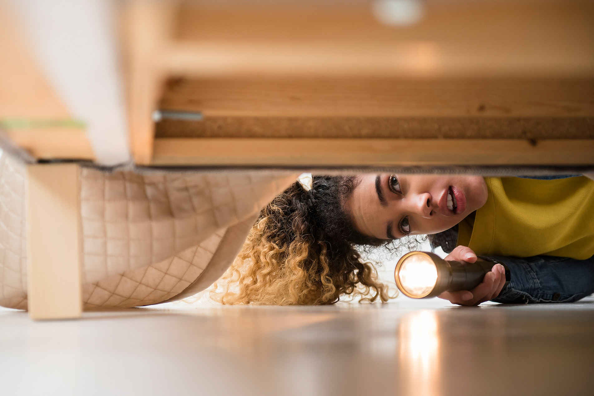 Stock photo, royalty-free, Mixed Race woman looking under bed with flashlight, security, strength, courage,