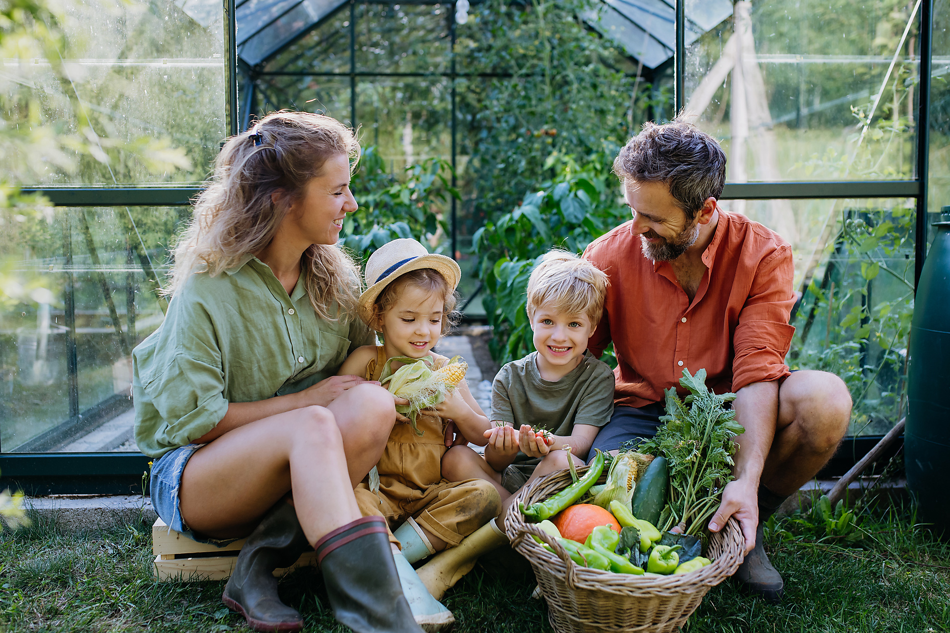 A young family with fresh harvest standing in a greenhouse, stock image, royalty-free, plant based food, vegetarian, vegan, sustainable, healthy eating,