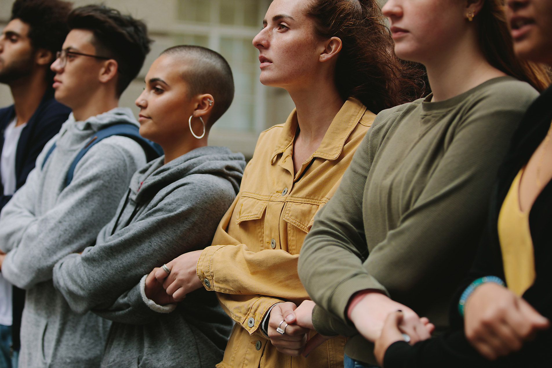 Group of protestors standing together holding hands in protest picket. Male and female activists protesting silently, We feeling, community, visual trends 2023, trend report, stock photo, royalty free