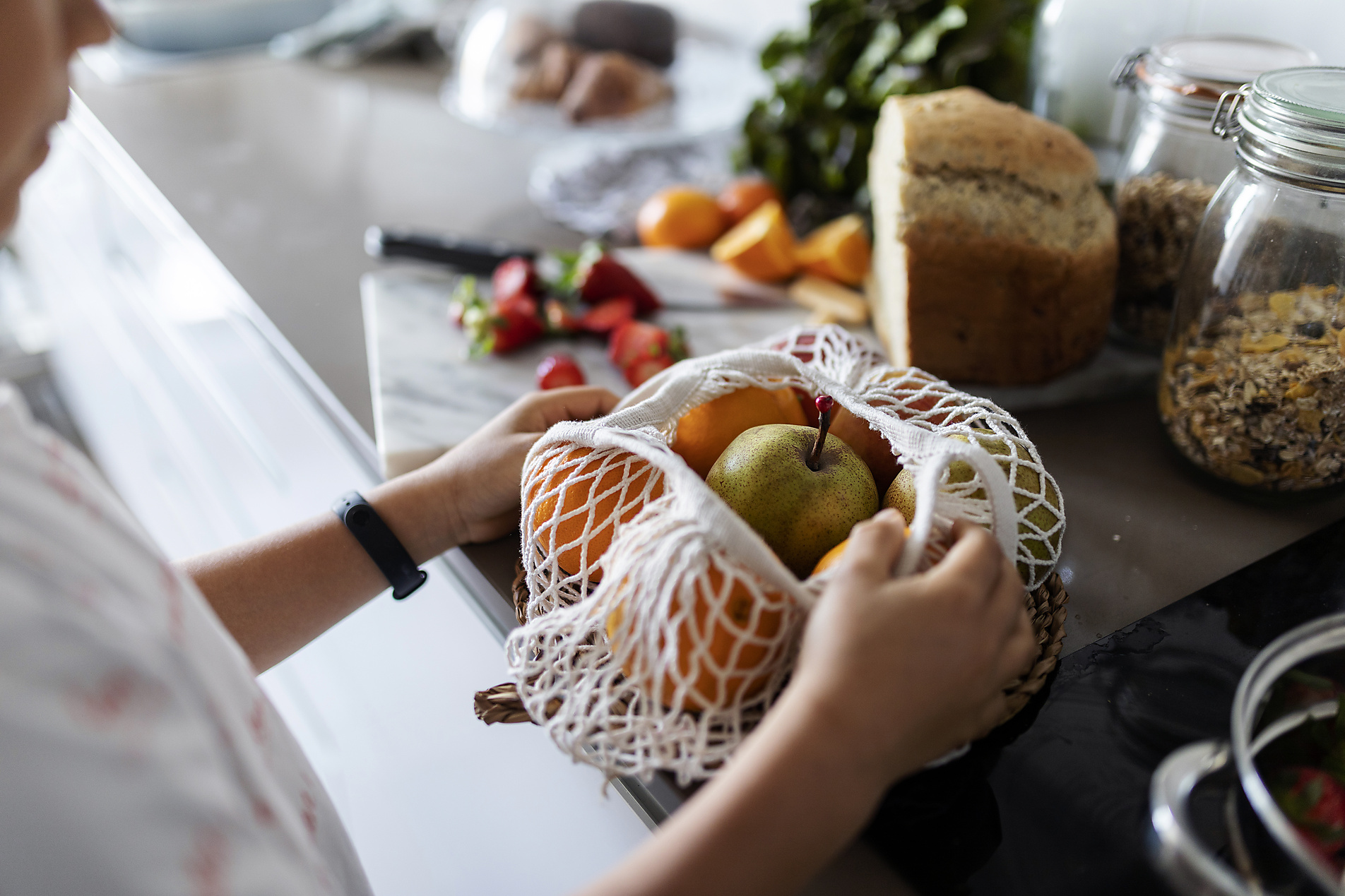Crop view of boy unpacking fruits on kitchen counter, stock image, royalty-free, plant based food, vegetarian, vegan, sustainable, healthy eating
