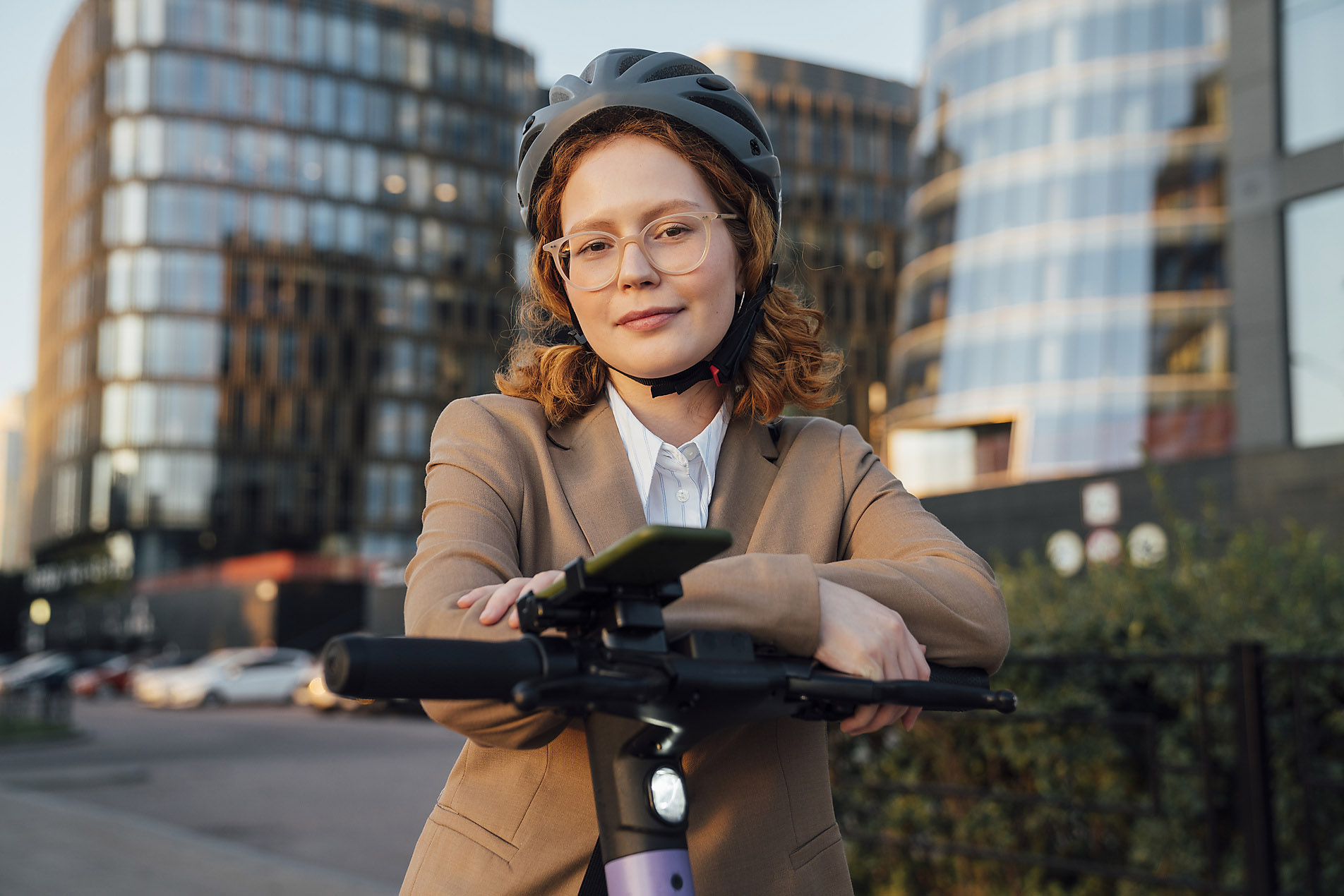 Beautiful business woman with glasses riding e-scooter in smart city navigating on her smartphone, connectivity, innovation, business, stock photo trends 2023, visual trends, royalty free