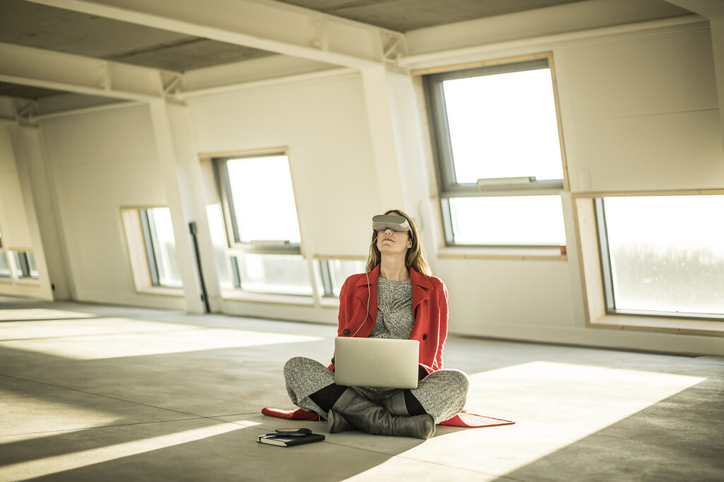 Stock photo, royalty free, pregnant business woman sitting on floor of new office space, using VR glasses and laptop, stock image, royalty-free, Malte Jäger, Westend61