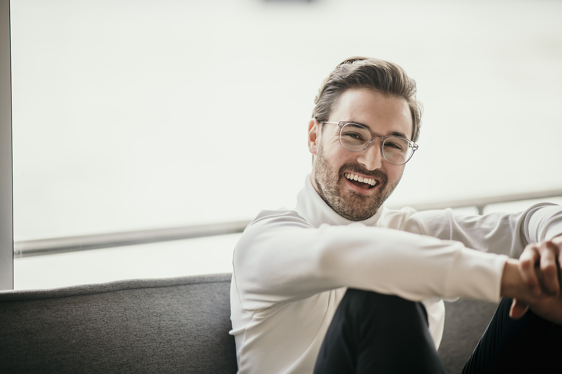 Smiling man sitting in front of bright window at home, stock image, royalty-free, malte jäger, westend61, home office, remote work
