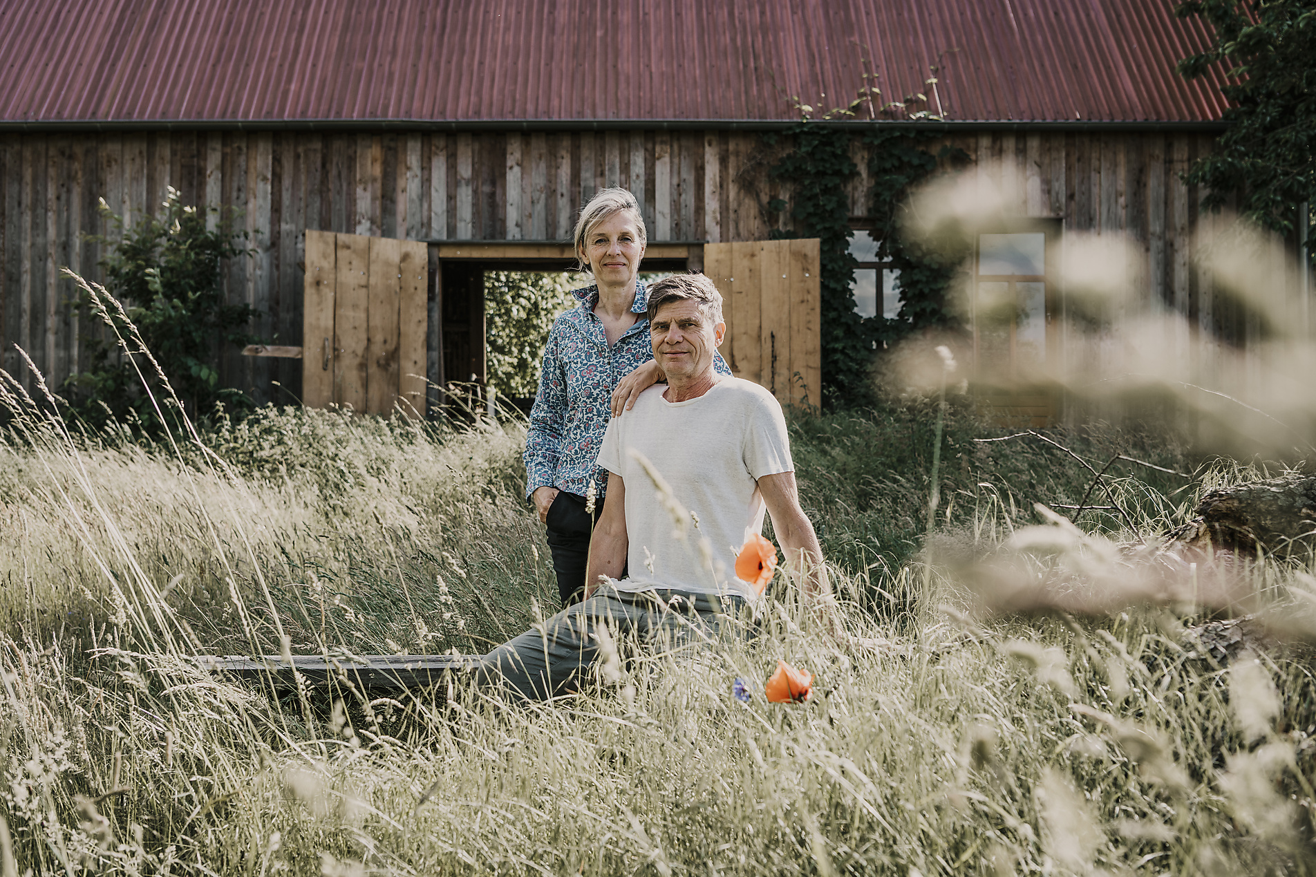 Man and woman sitting outdoors in front of a barn, countryside, westend61, malte jäger, stock image, royalty-free