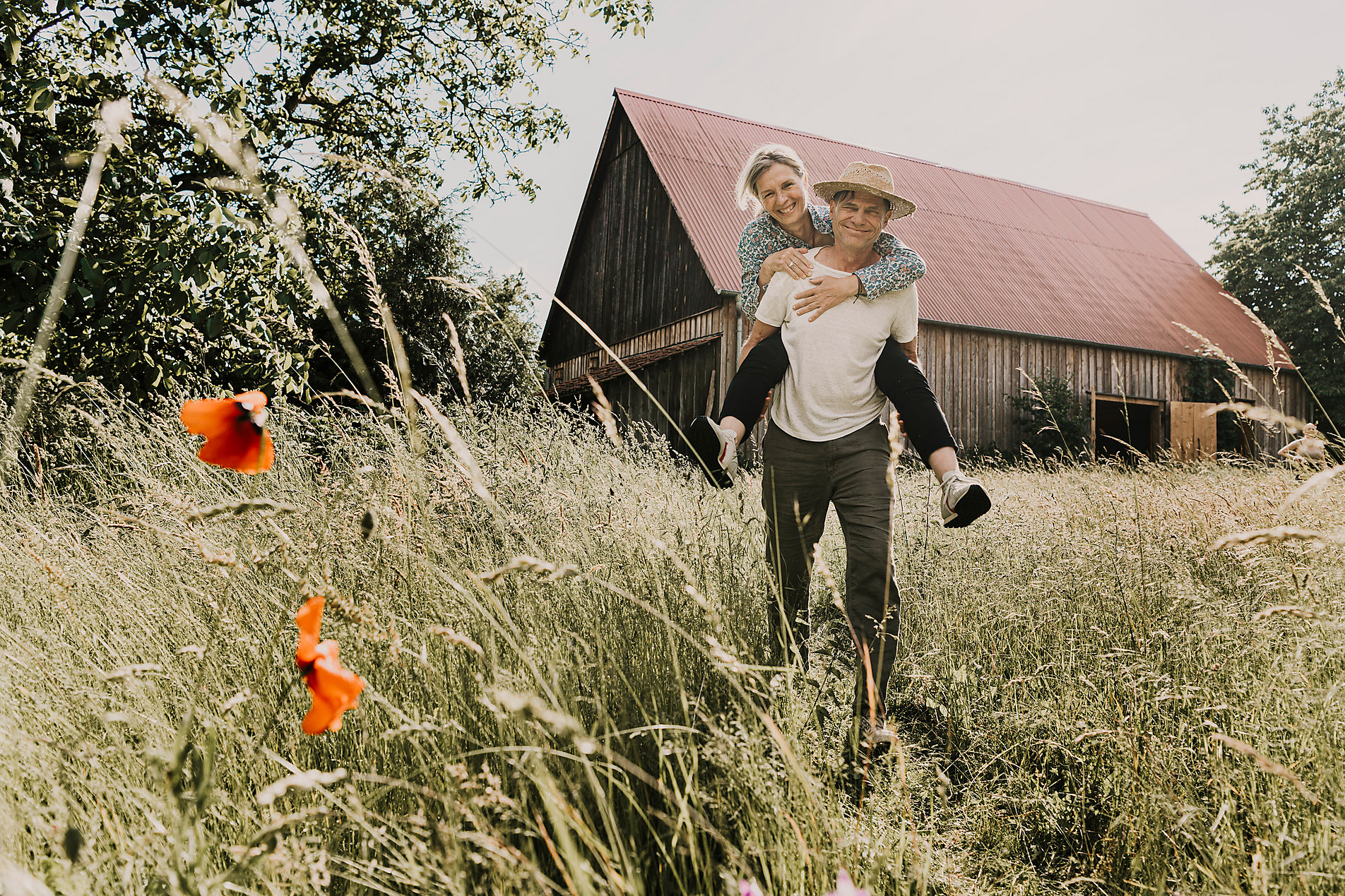stock image, royalty-free, Happy man piggybacking woman in front of barn, westend61, malte jäger, happiness, outdoors,