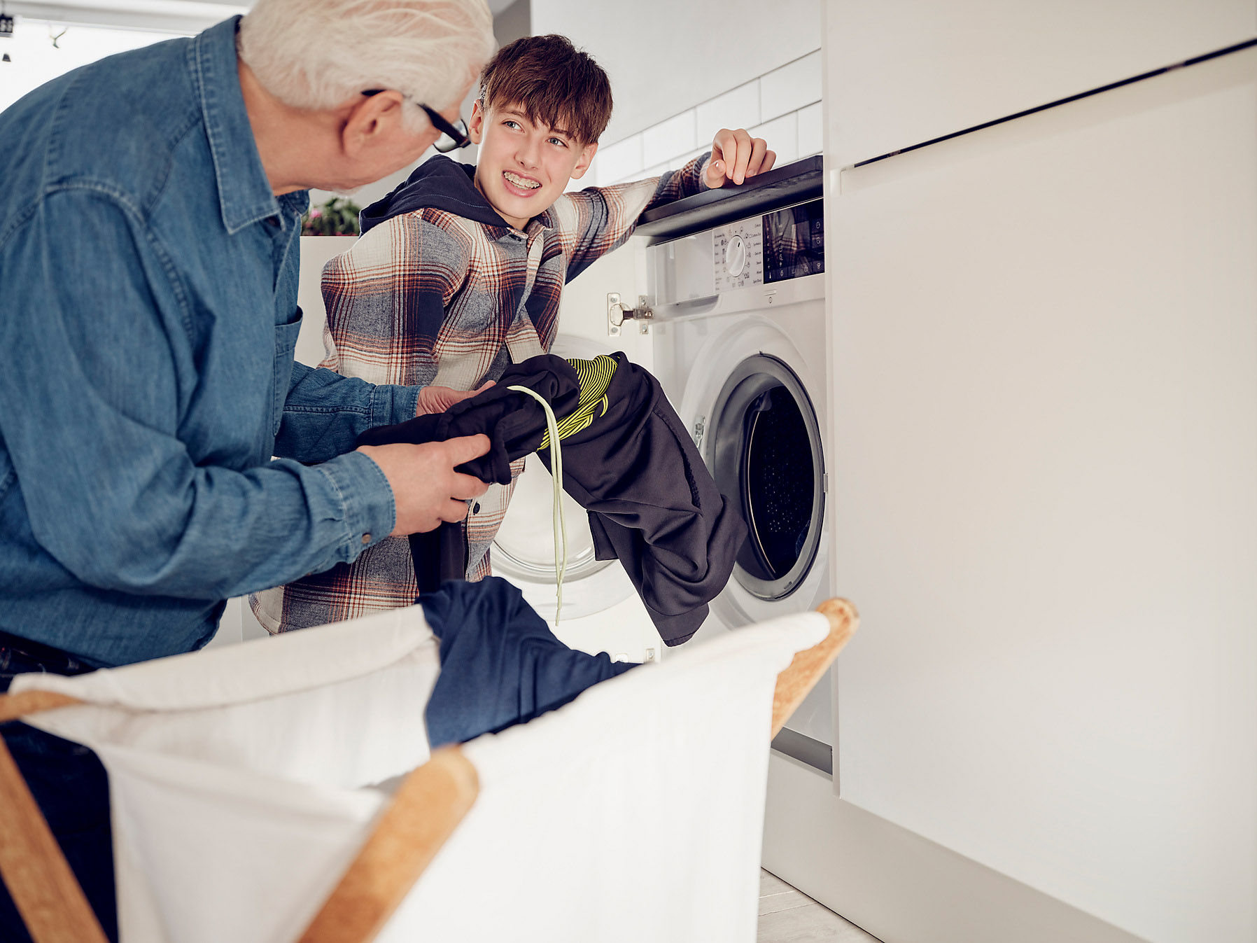 Grandson and grandfather put the laundry in the washing machine at home, sustainability, stock photo, royalty free