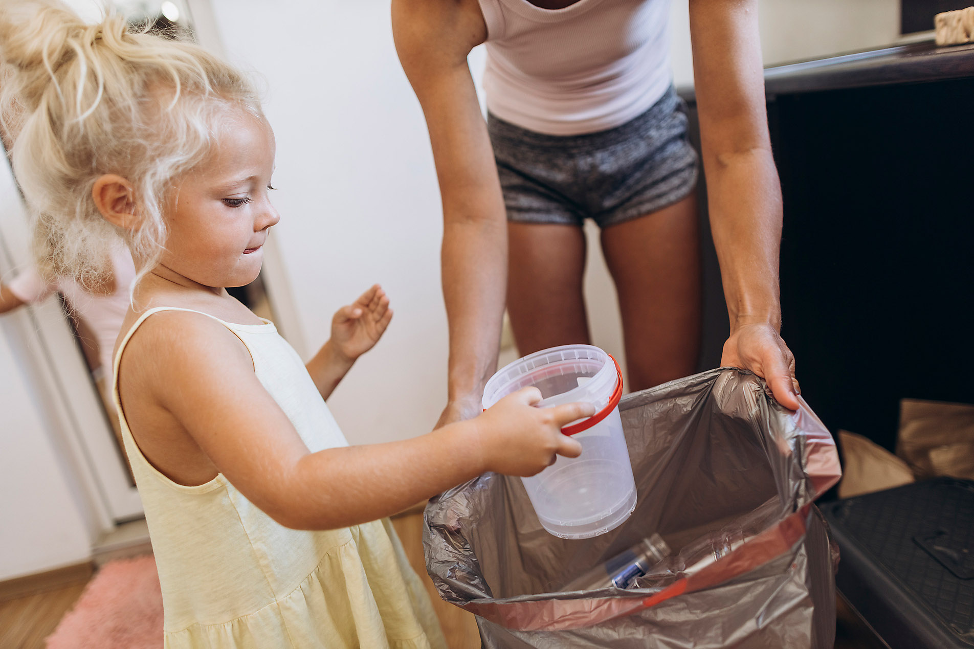 Mother and daughter throw plastic waste into recycling trash can, bin, stock photo, royalty free