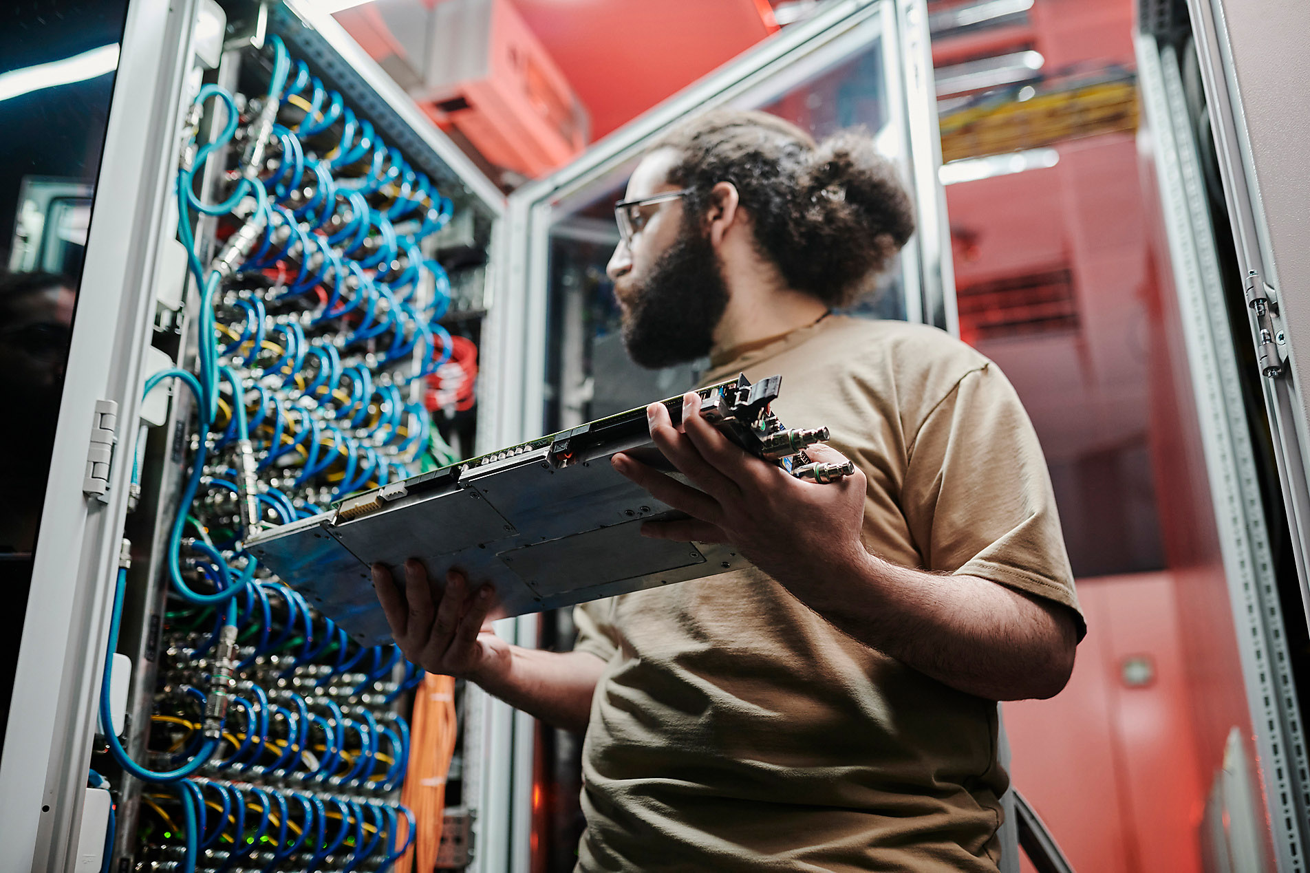 Technician looks at cables connecting a module with server, ai, artificial intelligence, big data, data security, server room, data analyst, westend61, trends 2023