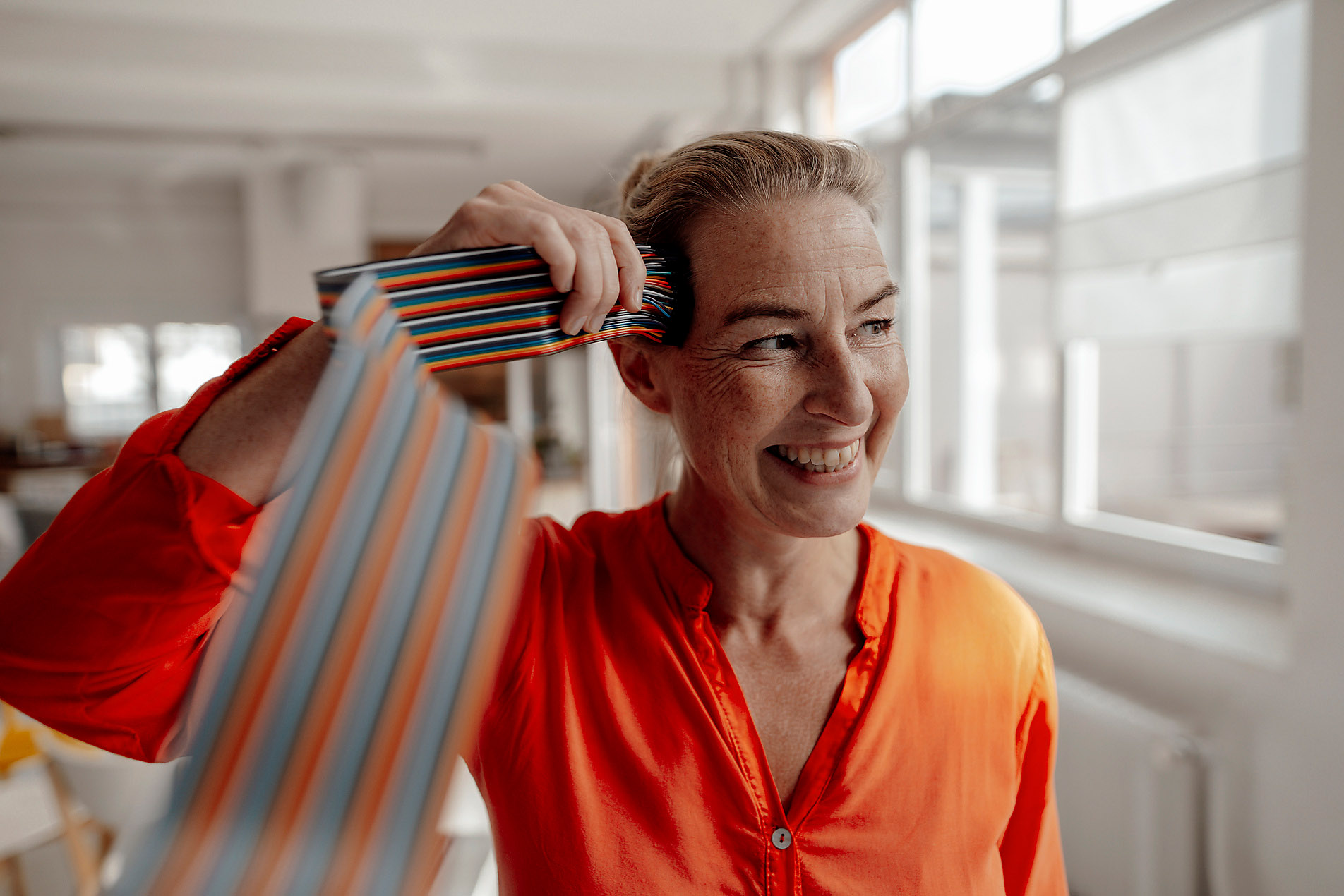 Cheerful businesswoman touching computer cables on head in office, stock image, royalty-free, connectivity, neuro ai, ai, artificial intelligence, big data, westend61, trends 2023