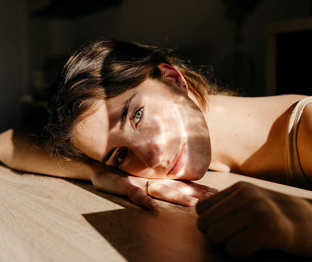 Porträt einer jungen Frau, die sich bei Sonnenlicht auf einen Holztisch lehnt, Resilienz, Stockfotografie,