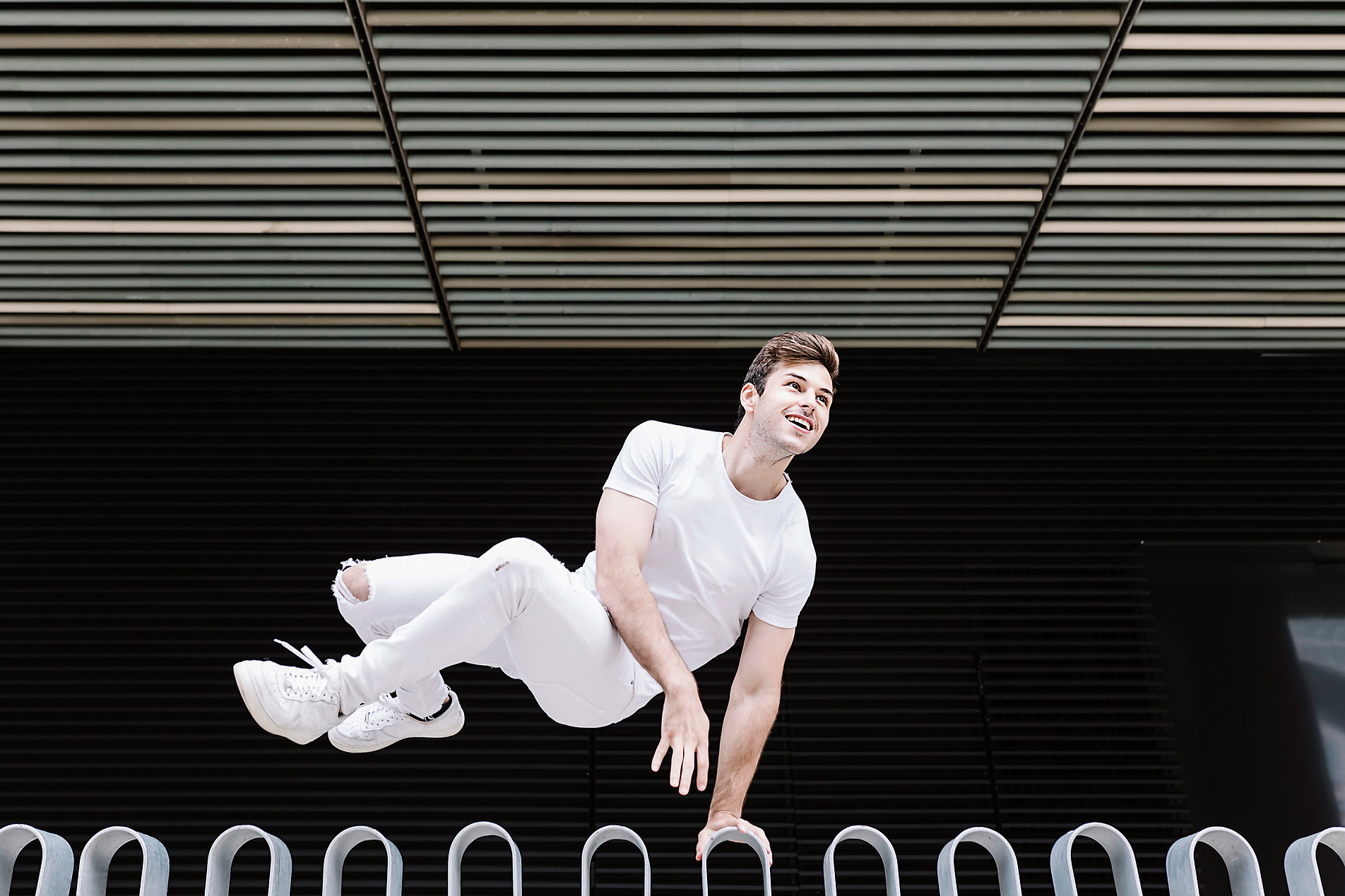young man opportunistically jumps over a railing with a smile while keeping his eyes firmly on a target, stock photo, royalty-free, Westend61, resilience, balance, activity, sport, overcoming obstacles, hurdle, ease