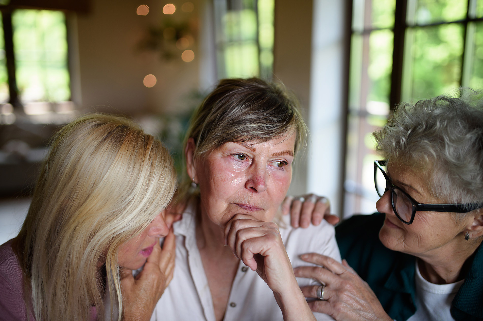 Female senior friends consloing a sad friend indoors at home, stock images, royalty-free,