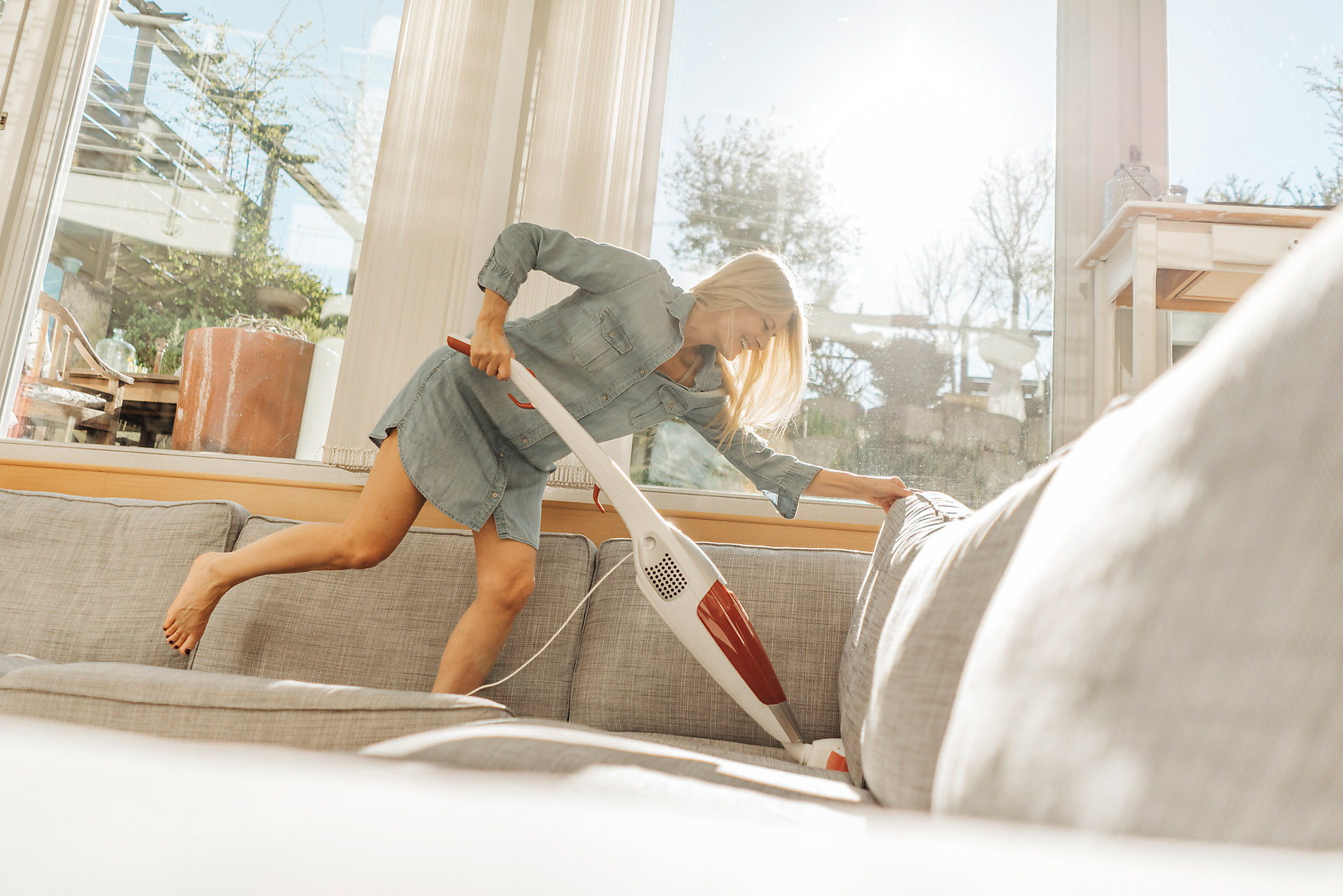 Happy woman at home hoovering the couch, Spring, season, spring, spring awakening, spring cleaning, nature, blossom, sunshine, change, new beginning, stock photo, royalty-free, Westend61