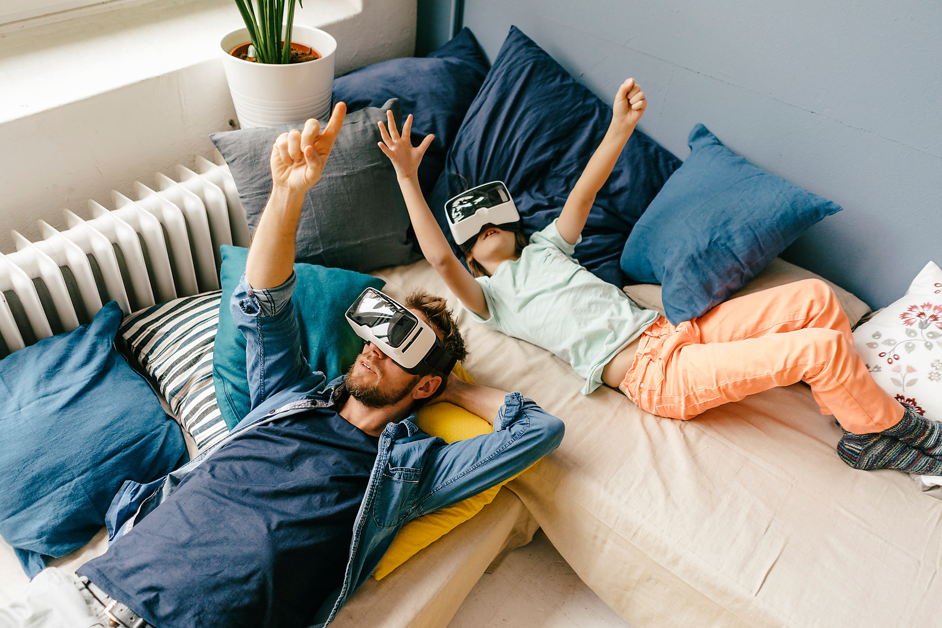 Father and son wearing VR glasses lying down at home exploring the metaverse, stock image, westend61, royalty-free