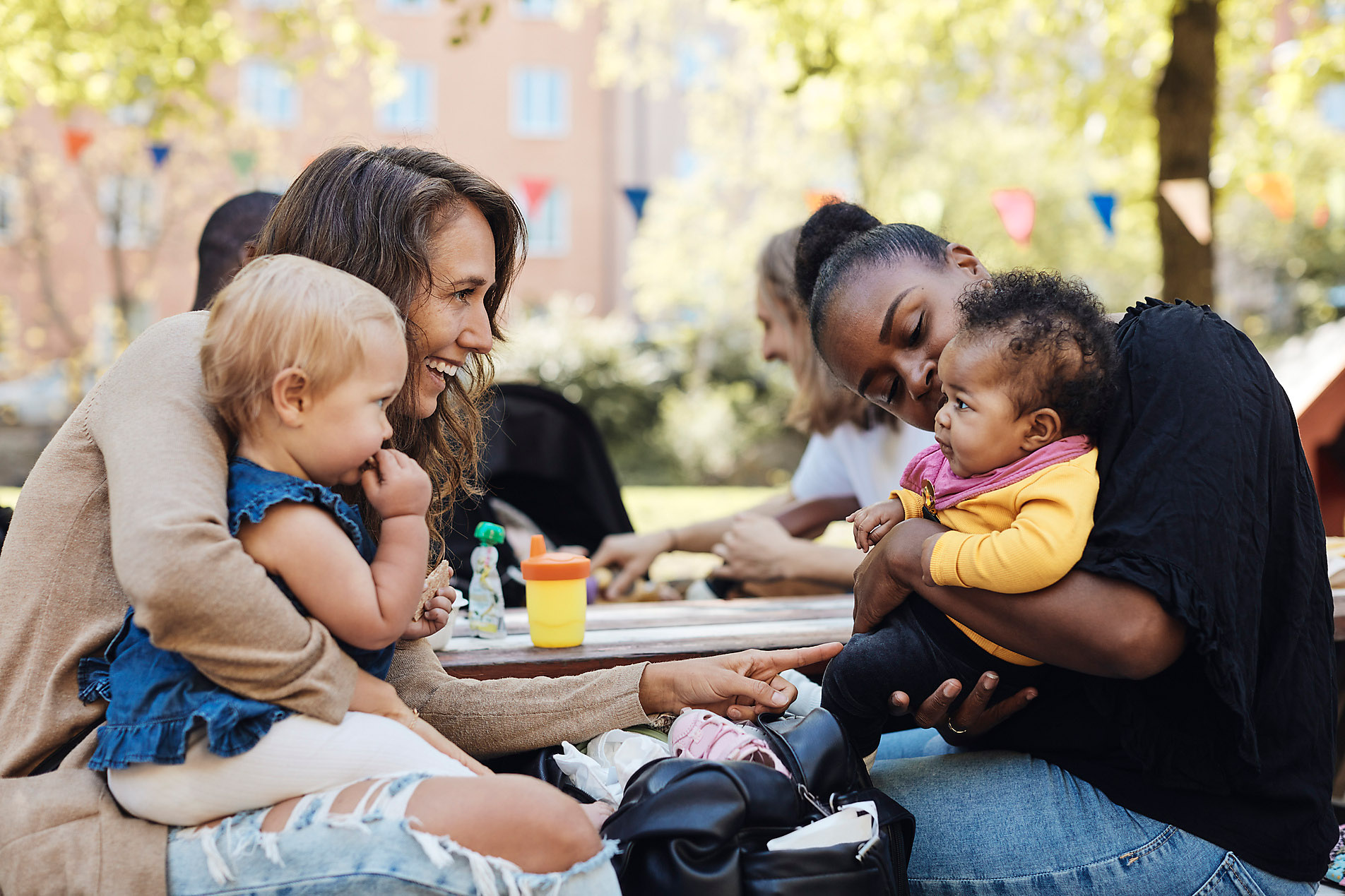 Mothers playing with daughters sitting at park, stock image, royalty-free