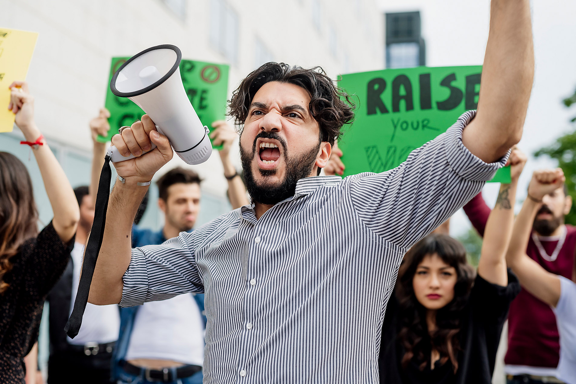 Man holding megaphone screaming with protestors on street, stock image, royalty-free,
