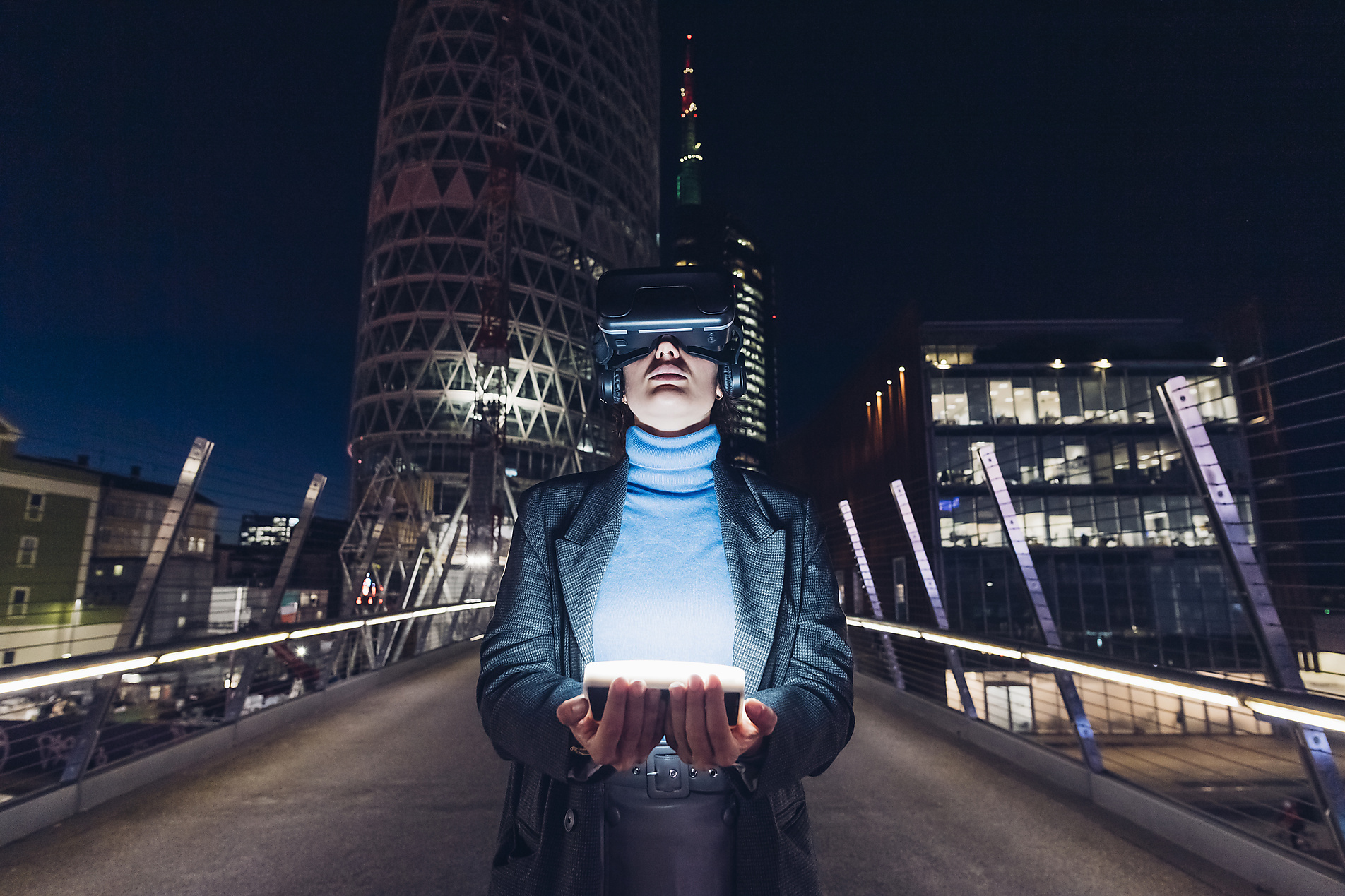 Businesswoman with virtual reality headset holding LED light on bridge in city, stock image, royalty free, metaverse