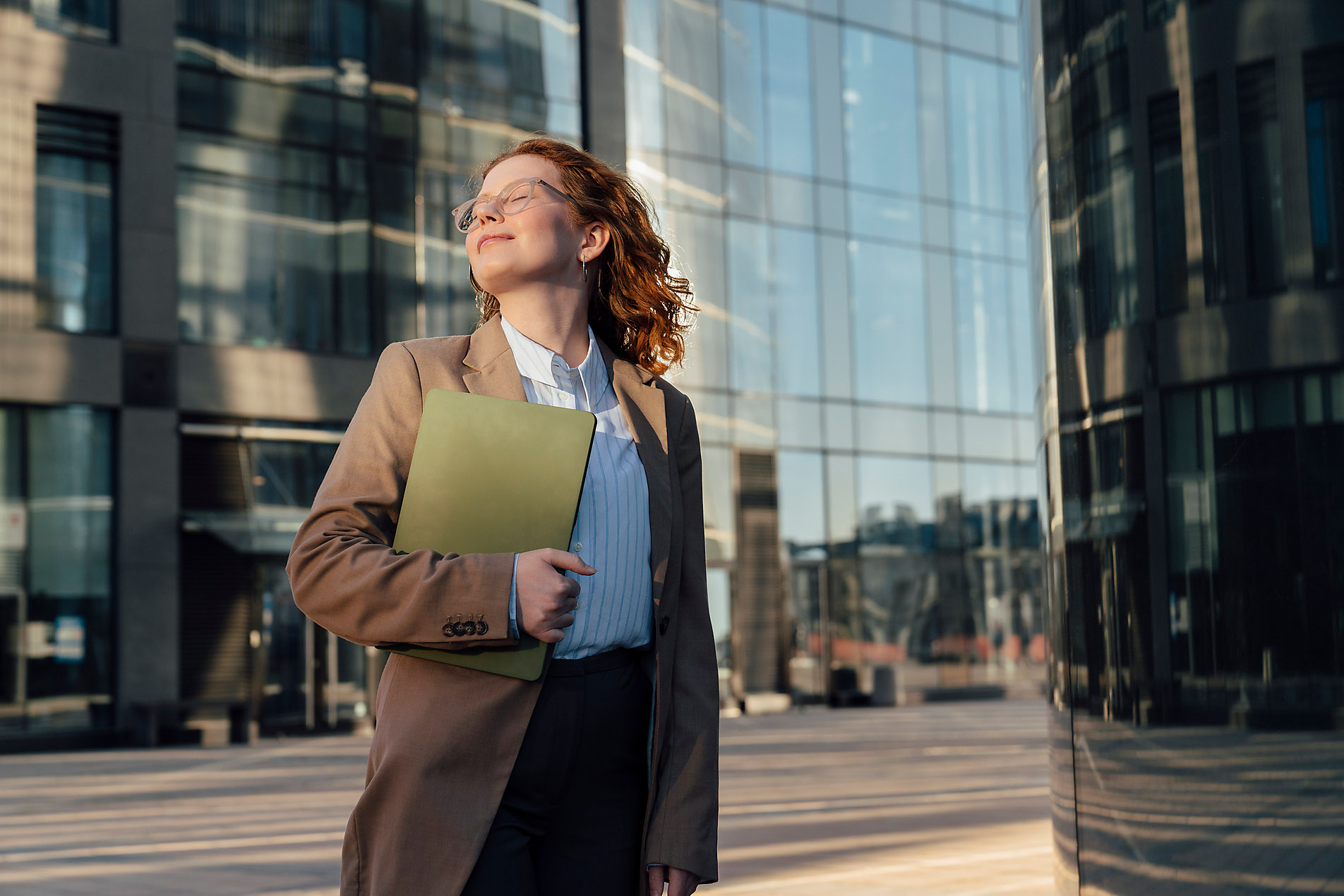 Smiling businesswoman with eyes closed and laptop by office building, Spring, season, spring, spring awakening, spring cleaning, nature, blossom, sunshine, change, new beginning, stock photo, royalty-free, Westend61
